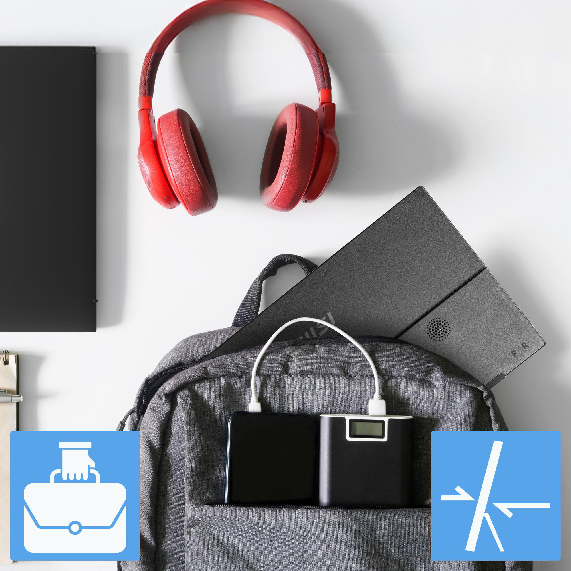 Rote Kopfhörer, ein Rucksack mit einem Laptop und eine Powerbank, die ein Telefon auf einer weißen Oberfläche auflädt.
