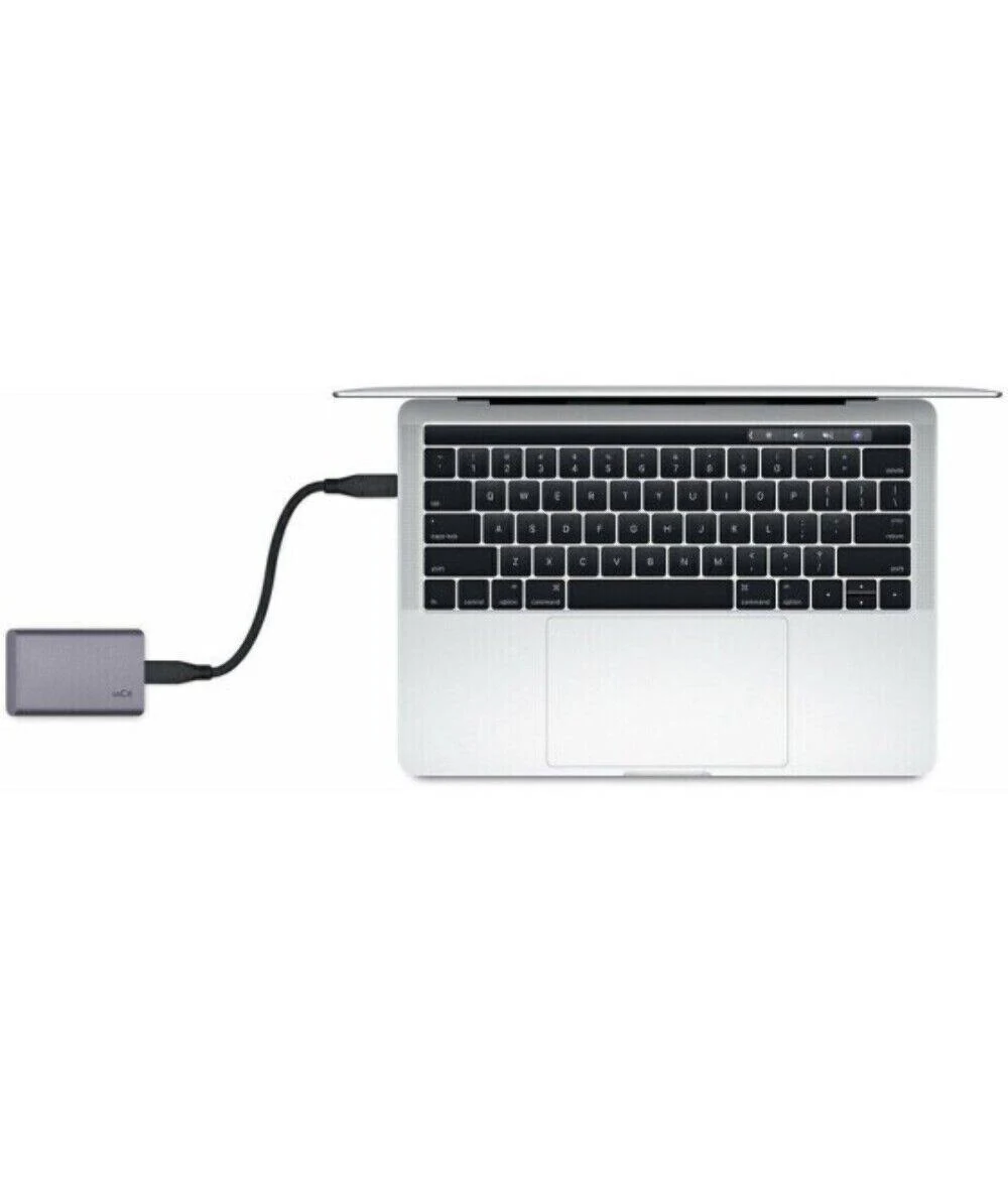 Una computadora portátil con teclado negro está conectada a un disco duro externo gris mediante un cable negro. Fondo blanco.