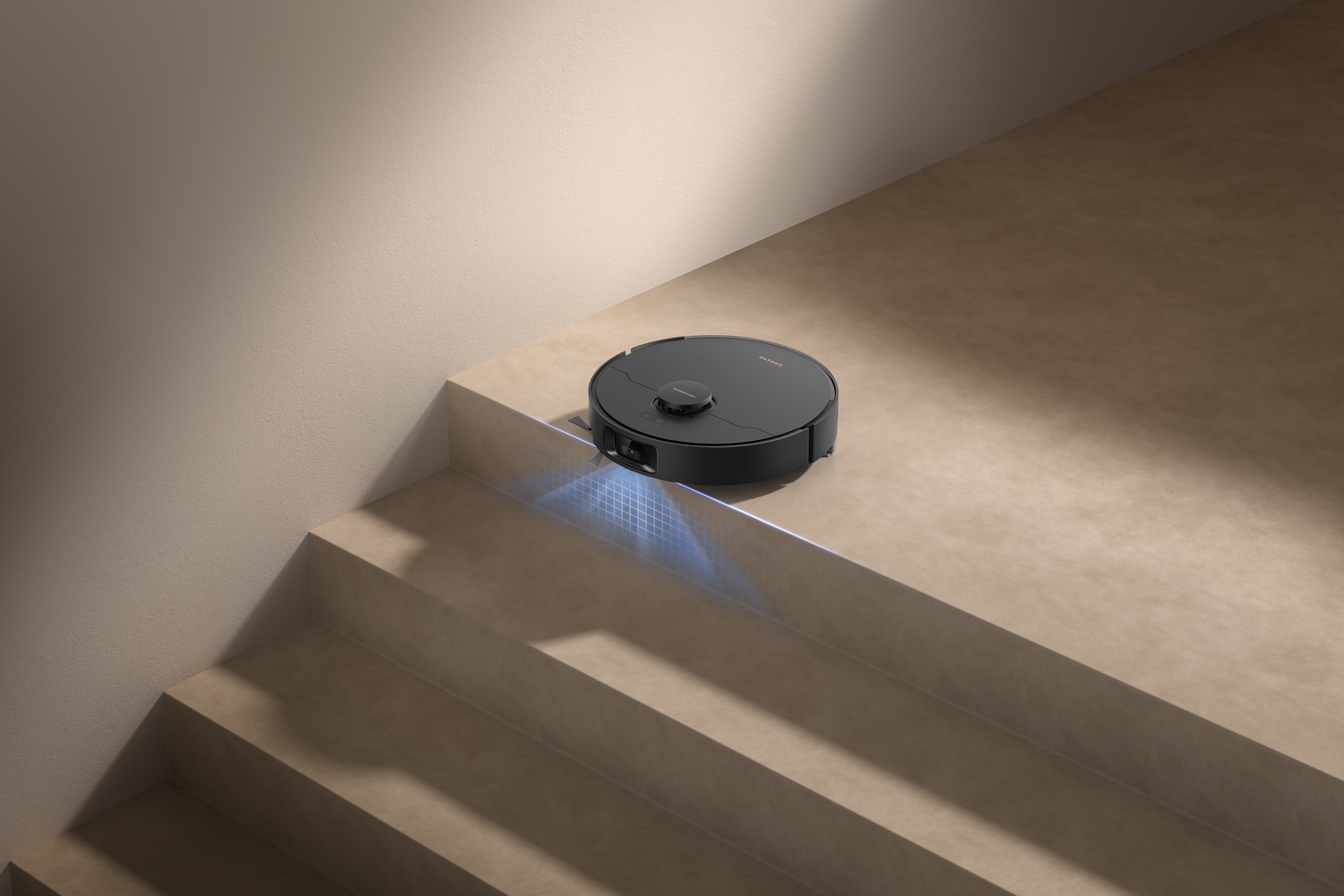 Una aspiradora robot negra está en un escalón. La escena incluye escaleras, paredes beige y luz azul.