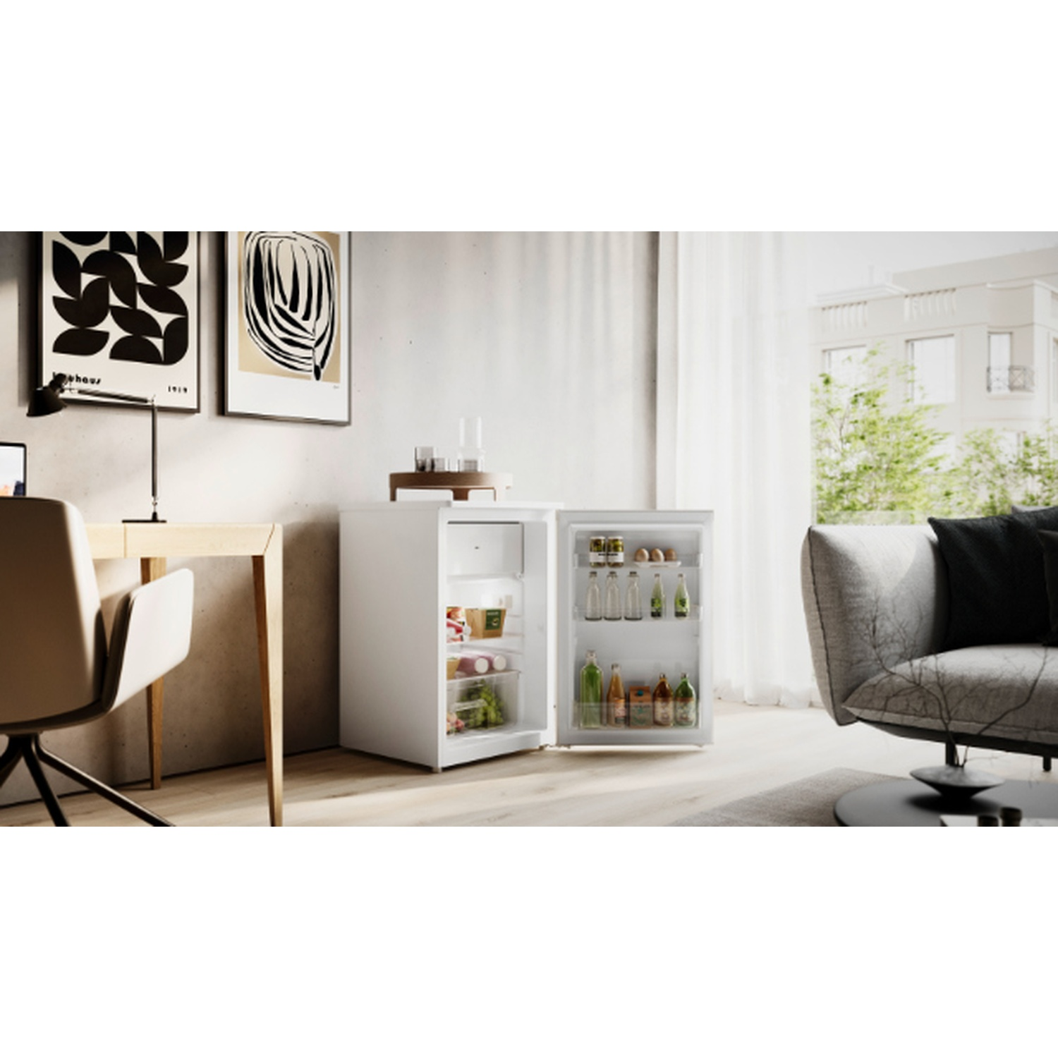 Un mini-frigo bianco con la porta aperta, che rivela cibo e bevande. Nelle vicinanze ci sono una scrivania, una sedia e un divano grigio. Opere d'arte appese al muro.