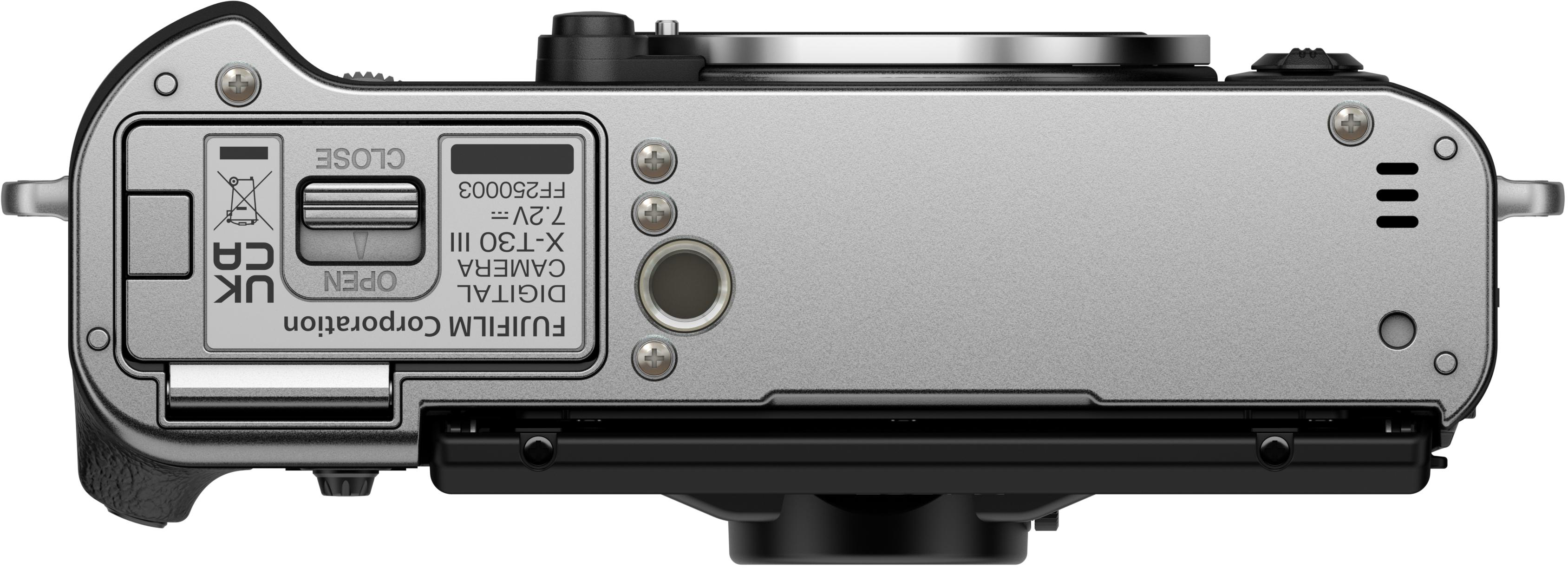 Fotocamera Fujifilm argentata, vista dall'alto. Include vano batteria, info modello, viti e pulsanti. Base nera.