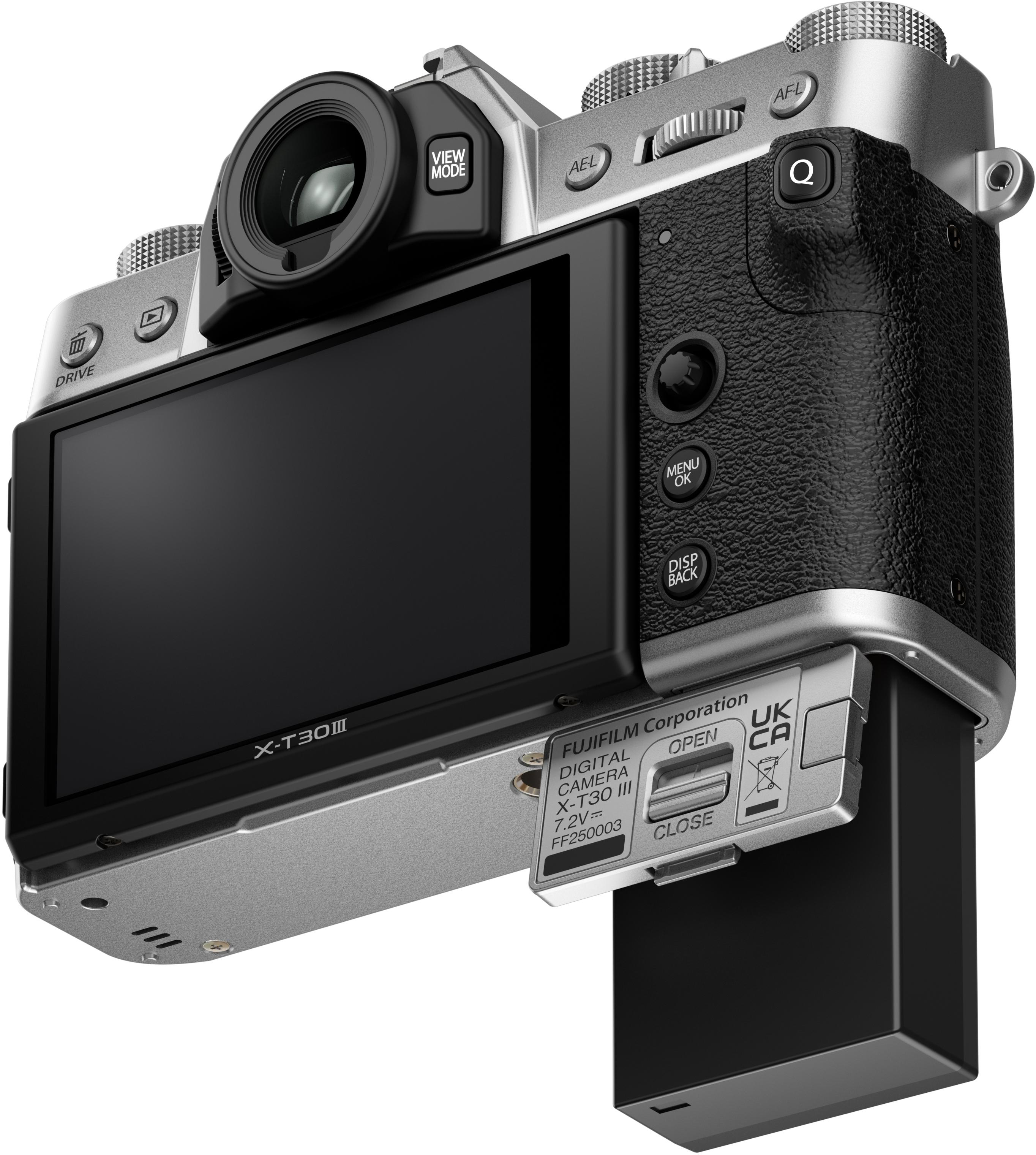 Una fotocamera Fujifilm X-T30 III argentata con schermo nero e batteria nera. Pulsanti e quadranti visibili.