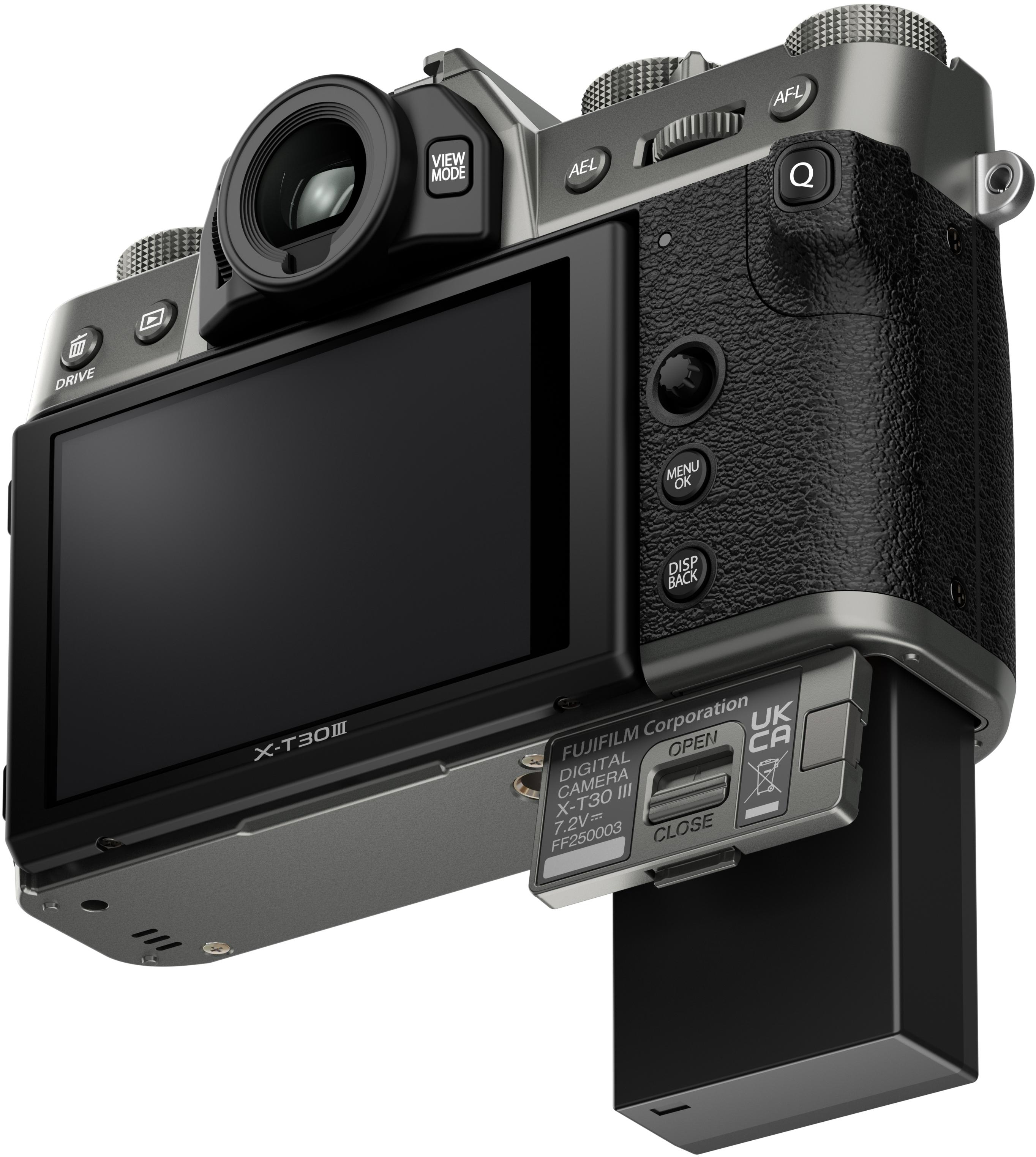 Eine silberne und schwarze Fujifilm X-T30 III Kamera wird gezeigt, mit geöffnetem Bildschirm und Akkufach.