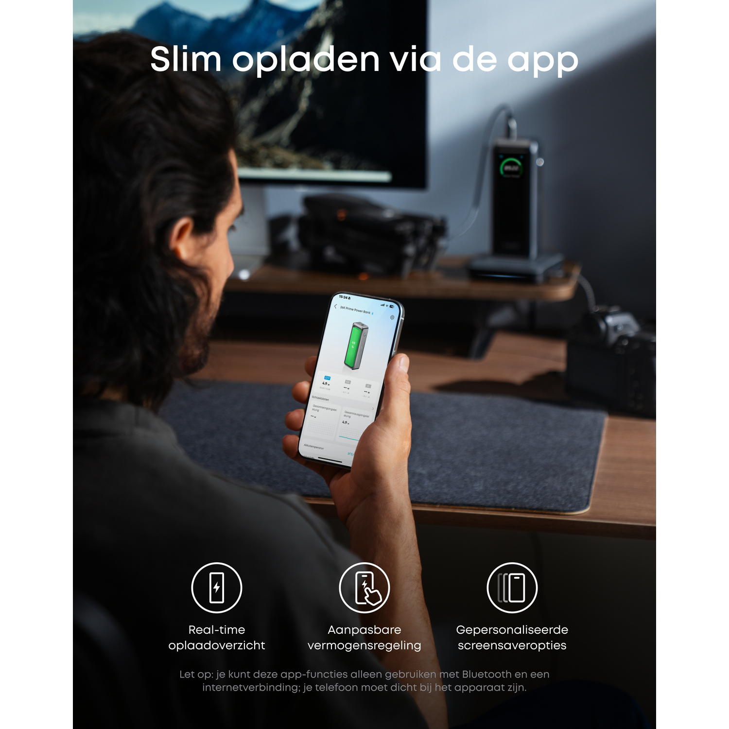 A man holds a phone displaying a power bank app. A charger is on a desk. Text: Slim charging via the app, real-time overview.