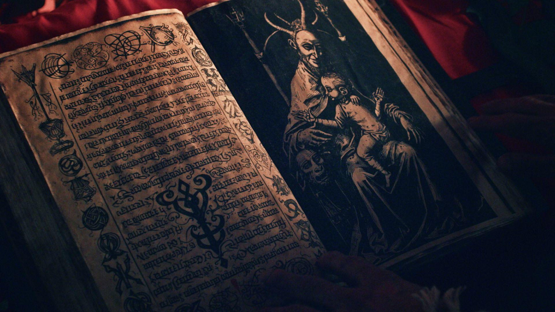 Offenes Buch mit alter Schrift auf einer Seite und einem Teufel mit einem Kind auf der anderen. Roter Stoff im Hintergrund.