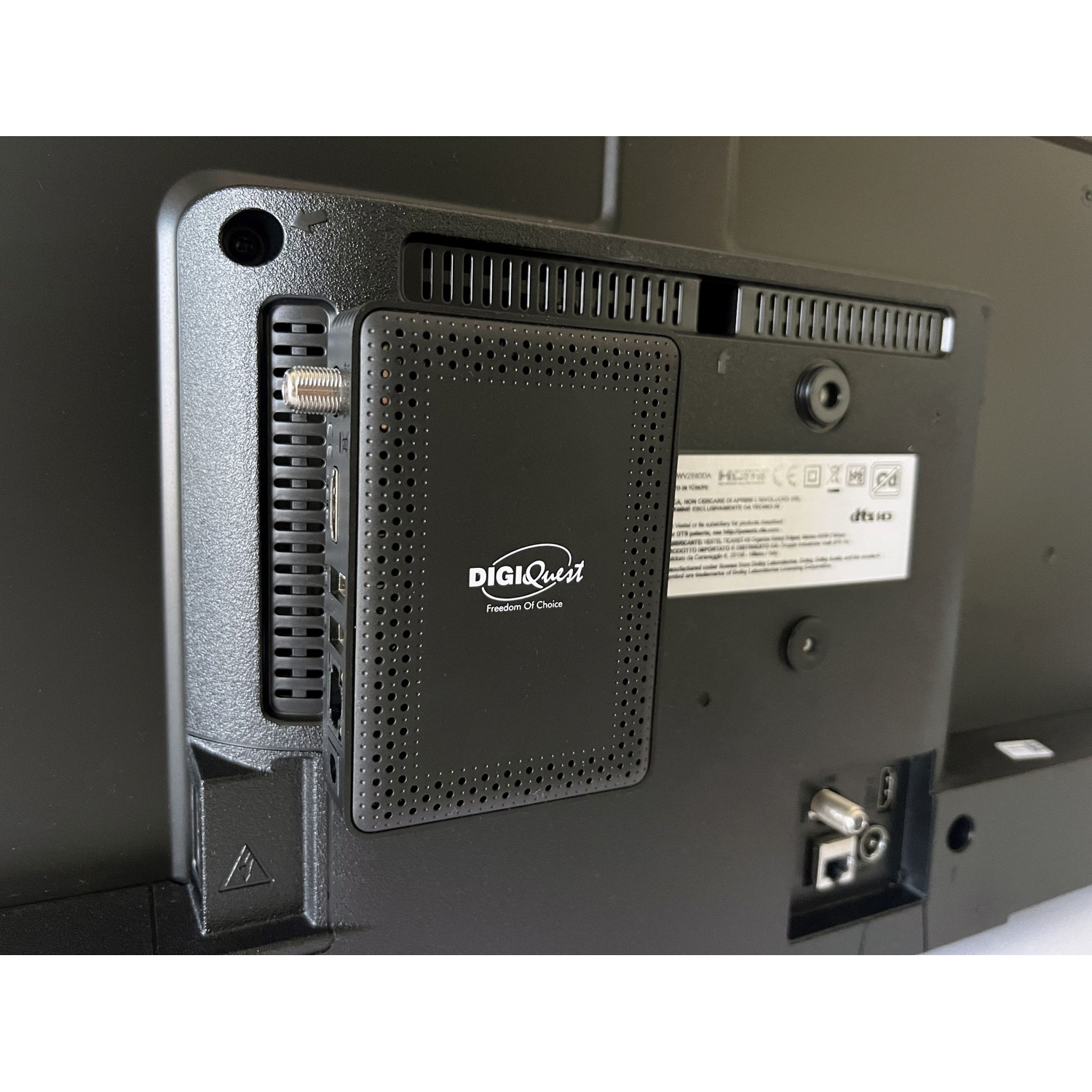 Il retro di una TV nera con un dispositivo DigiQuest collegato. Sono visibili varie porte e ventilazione. Il marchio è DigiQuest.