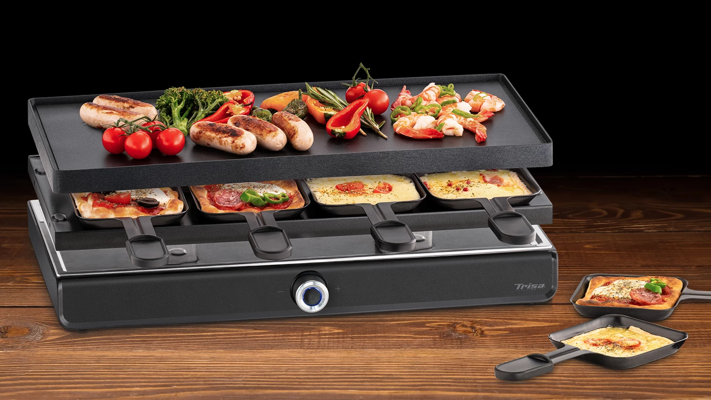Grill per raclette con salsicce, gamberi, verdure e pizza. Il livello inferiore contiene formaggio e pizza. Sfondo in legno.