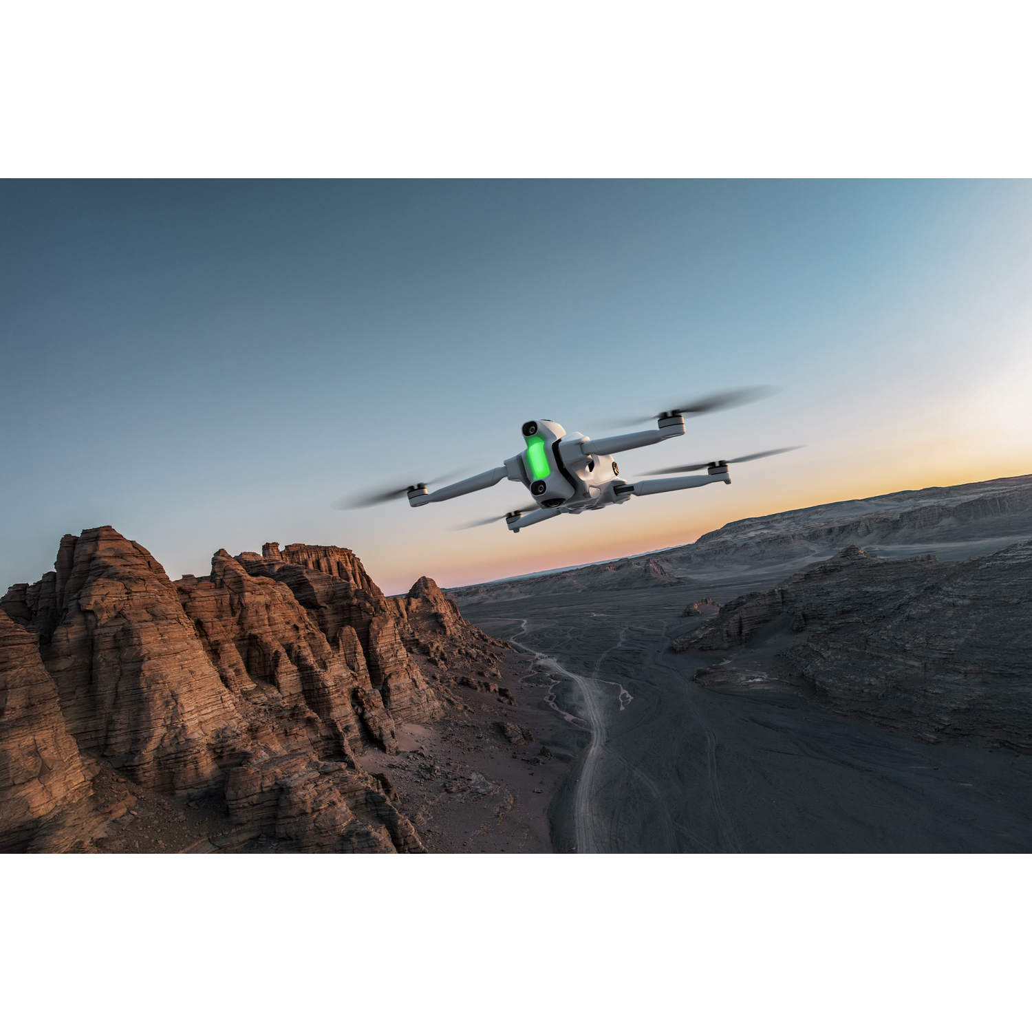 Een drone vliegt over een woestijnlandschap. Rotsformaties op de voorgrond, stoffige vallei en blauwe lucht op de achtergrond.
