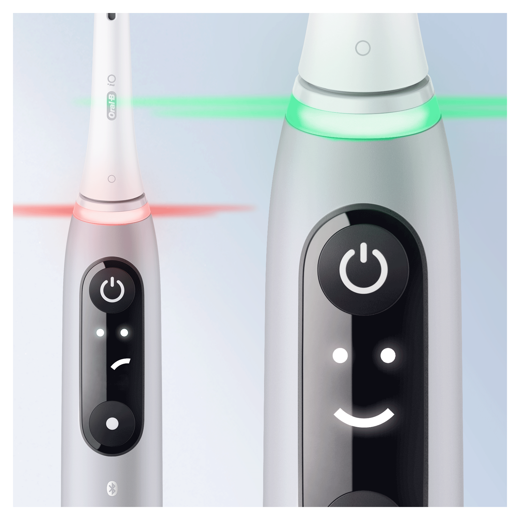 Dwie elektryczne szczoteczki do zębów z przyciskami zasilania i wskaźnikami świetlnymi, jedna z czerwonym, druga z zielonym światłem.