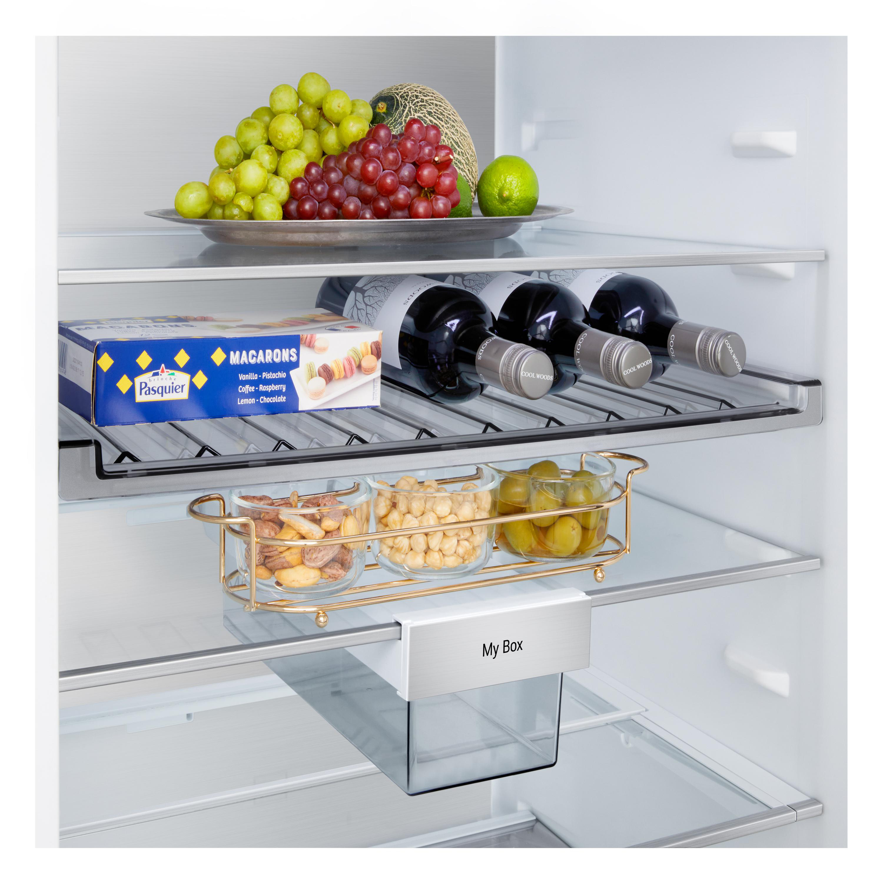 In einem Kühlschrank: Trauben, Melone, Limette, Weinflaschen, Makronen, Nüsse und Essiggurken. Eine 'My Box'-Schublade ist sichtbar.