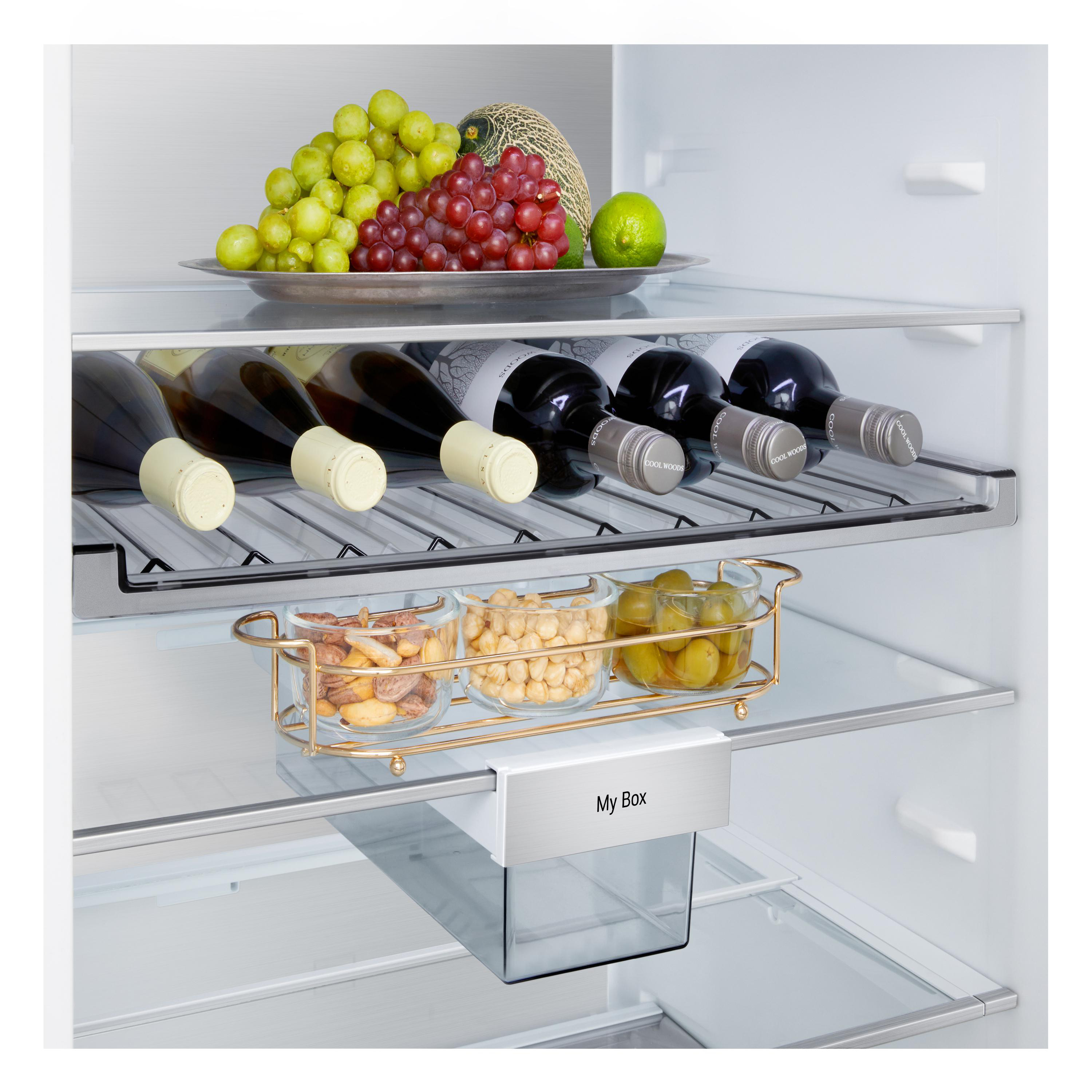 In einem Kühlschrank: Trauben, Melone, Weinflaschen, Snacks in Schalen und eine Limette. 'My Box' ist sichtbar.