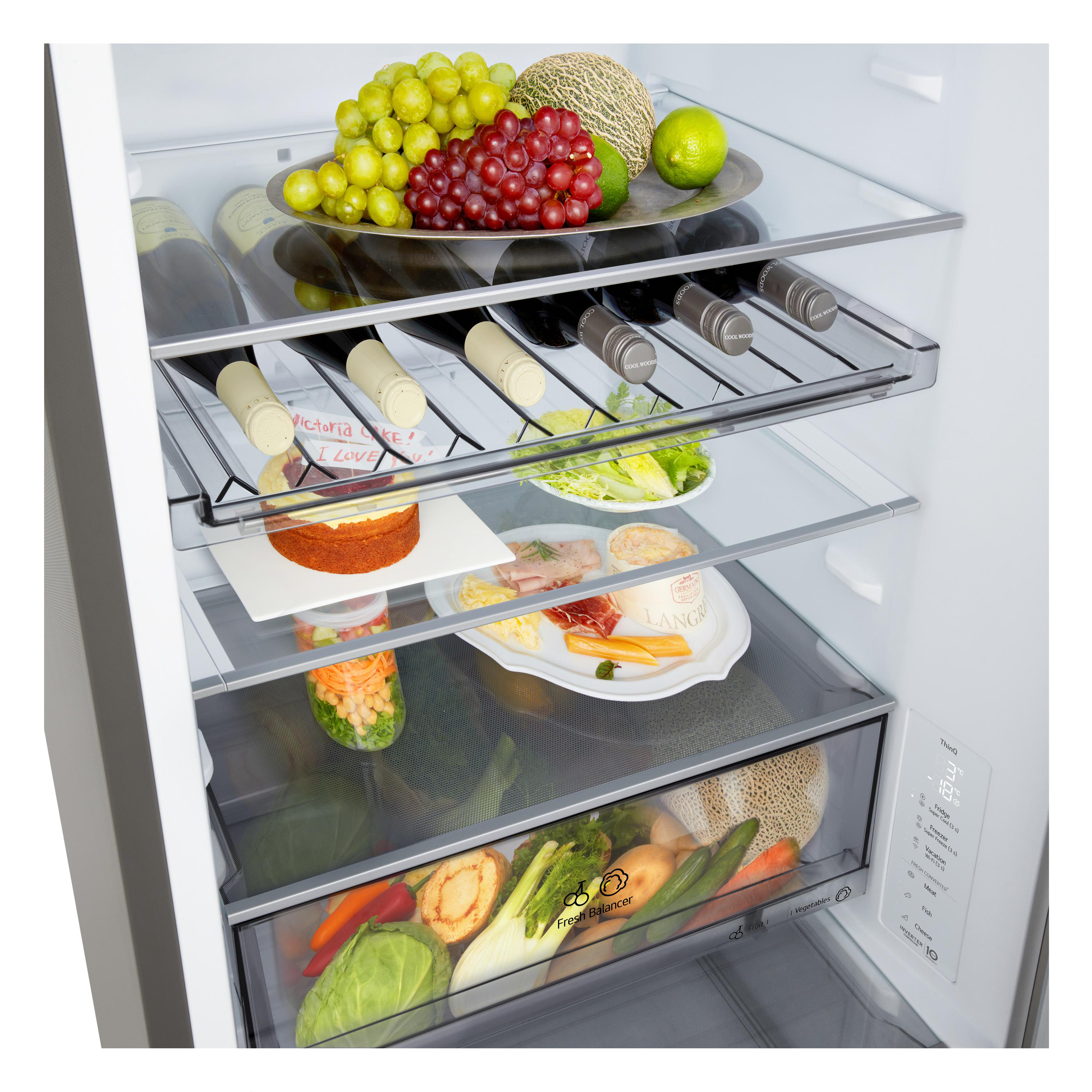 Offener Kühlschrank mit Obst, Gemüse, Weinflaschen und zubereiteten Speisen auf Glasböden. Die Tür ist leicht geöffnet.