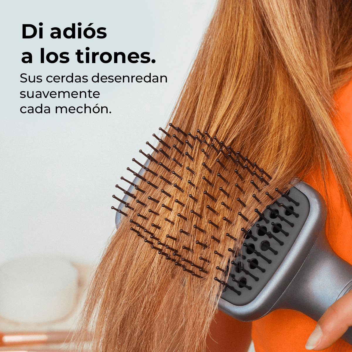 Una persona cepilla cabello largo y castaño claro con un cepillo gris. La persona usa una camisa naranja. Texto en español aparece a la izquierda.