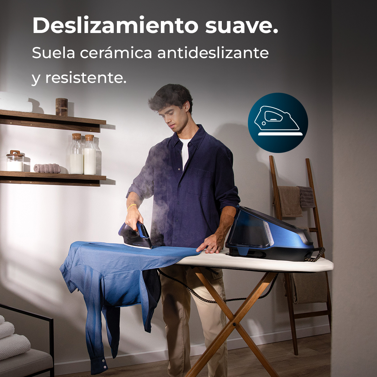 Un hombre plancha una camisa azul sobre una tabla de planchar blanca. El vapor sale de la plancha. Una plancha azul está en la tabla.