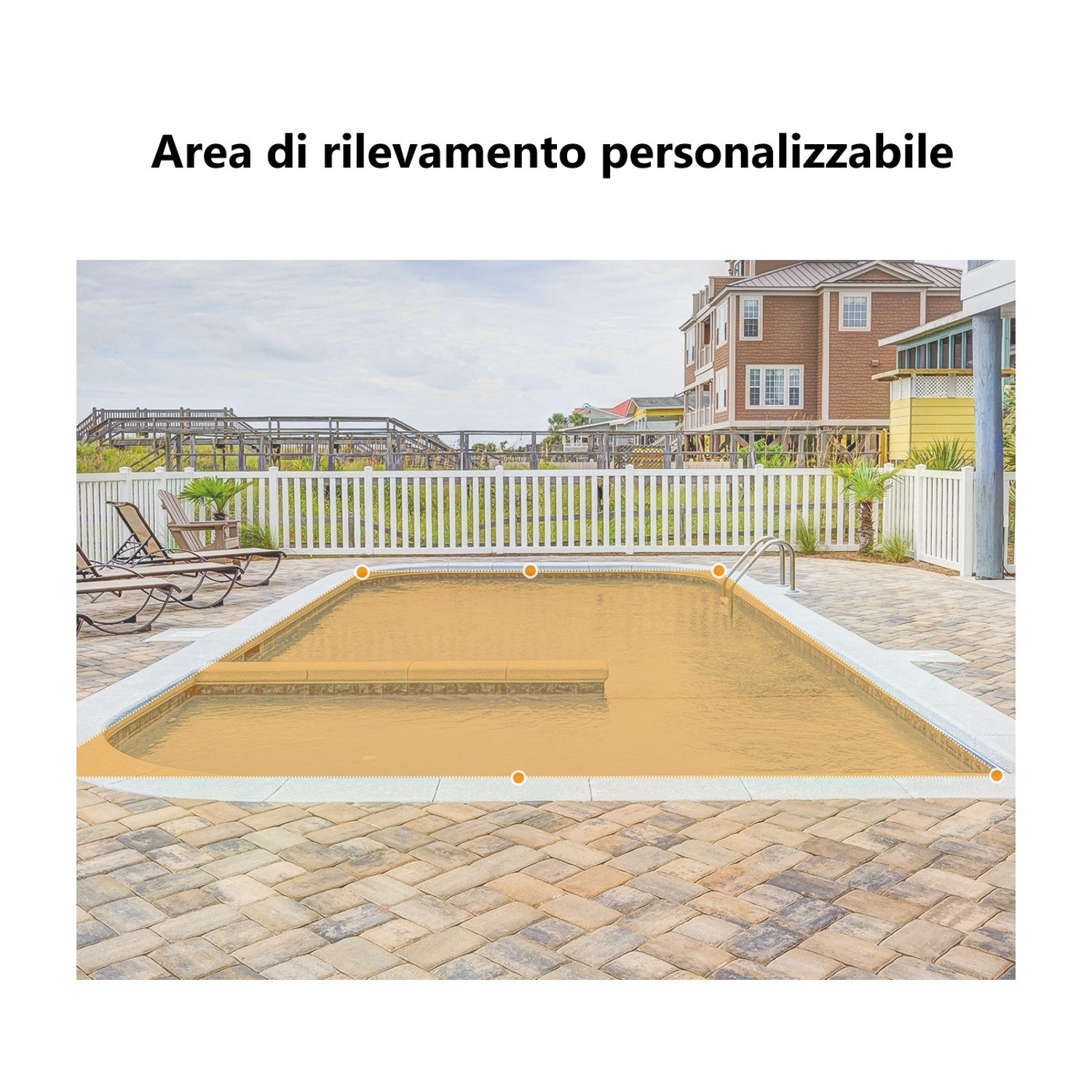 Una piscina con patio in pietra. Recinzione bianca e case sullo sfondo. Sedie a sdraio a bordo piscina.