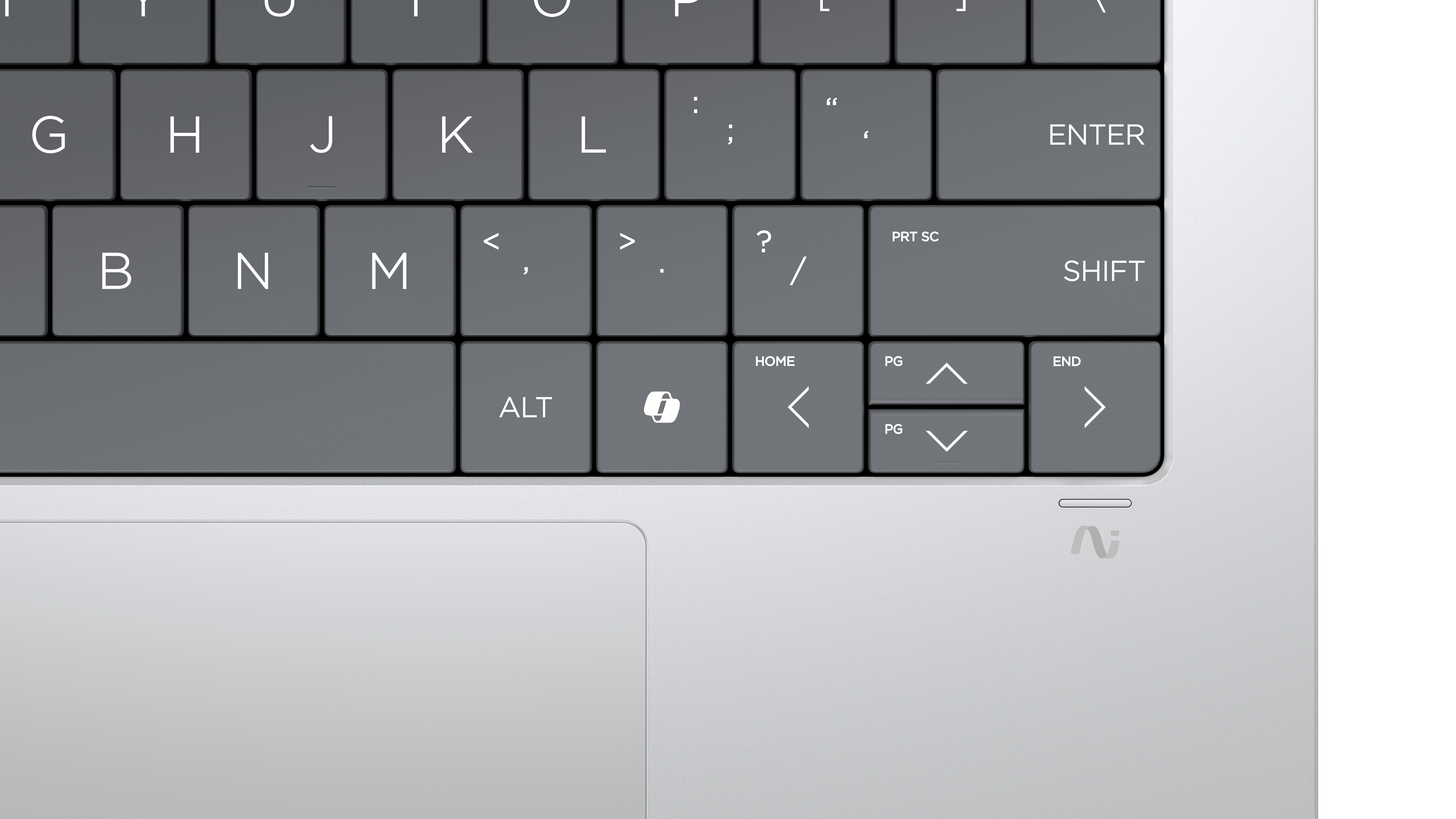 Zbliżenie klawiatury laptopa. Klawisze są szare z białymi literami. Zawiera klawisze Alt, Shift, Enter i strzałki. Srebrny gładzik.