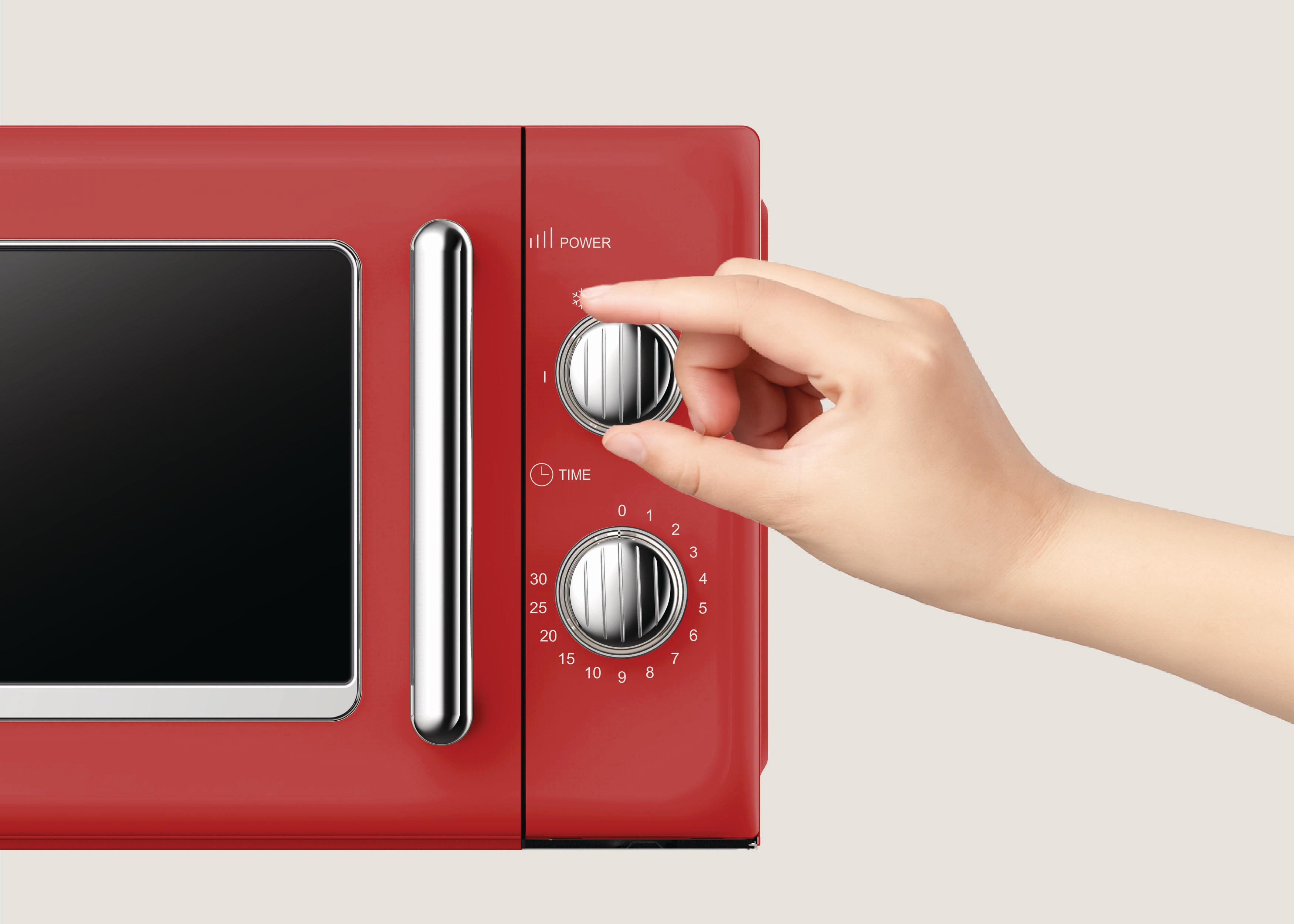 Ein rotes Mikrowellengerät, bei dem eine Hand den Leistungsregler dreht. Der Timer ist sichtbar. Heller beiger Hintergrund.