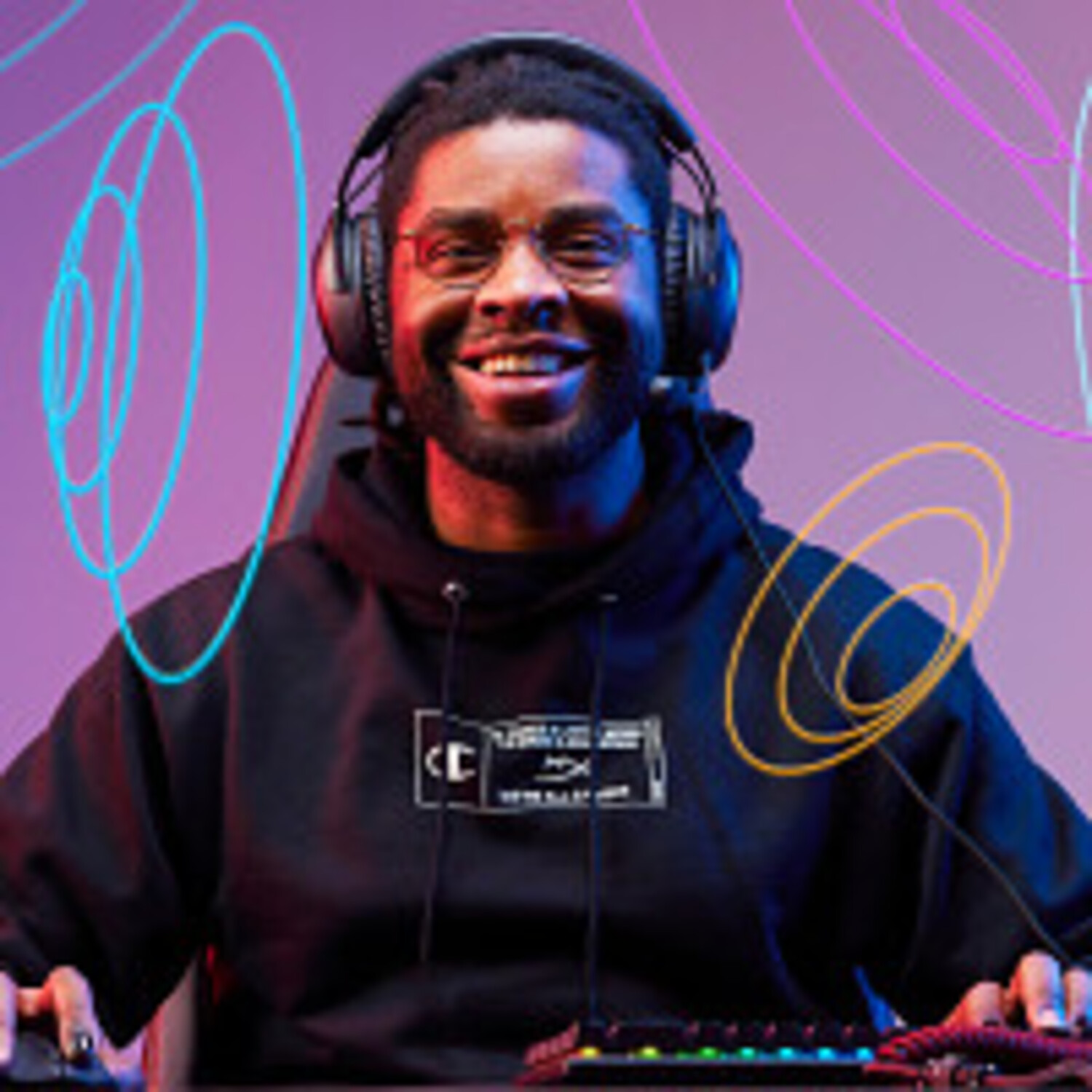 Un hombre negro sonriente con gafas y auriculares está jugando. Lleva una sudadera con capucha negra. Hay líneas coloridas en el fondo.