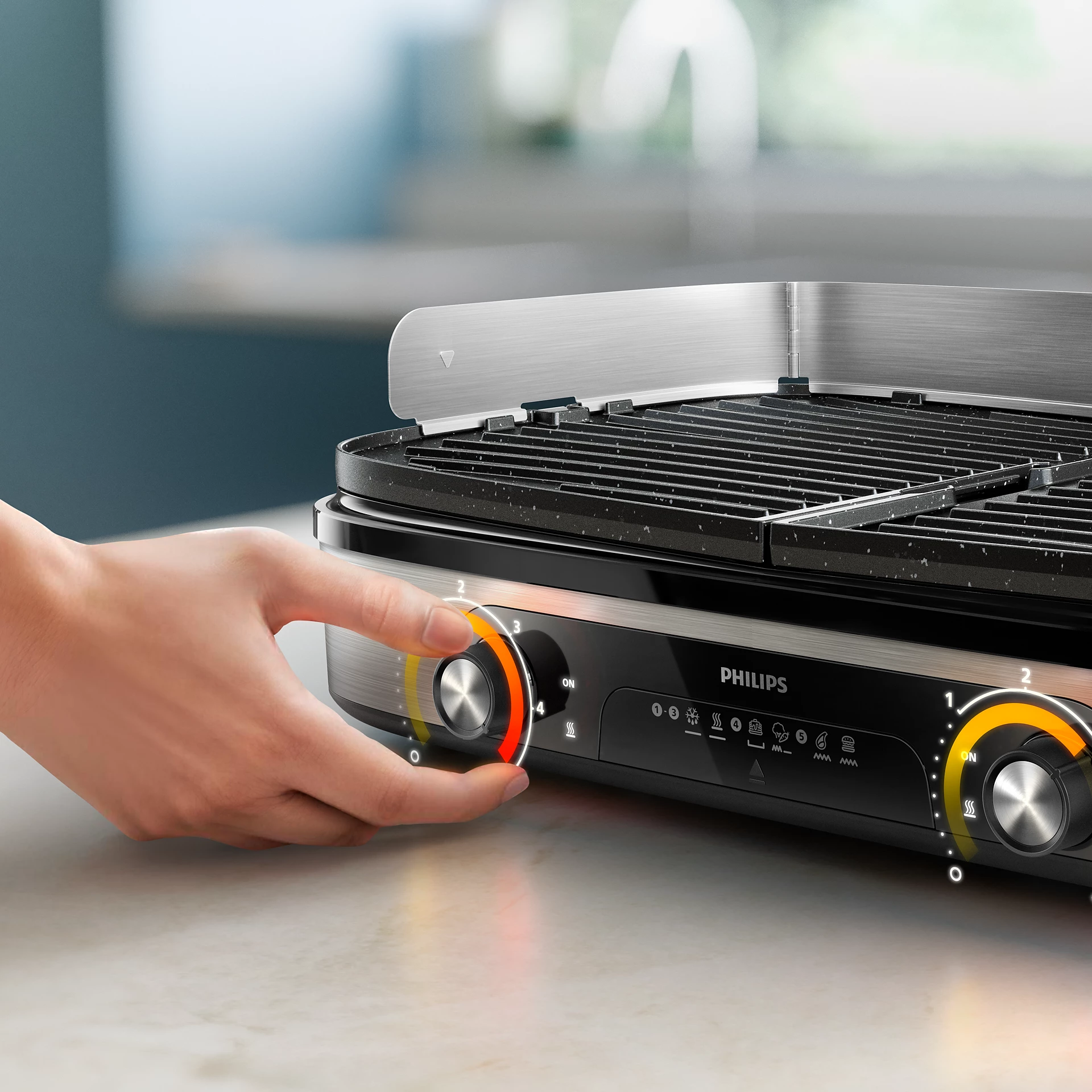 Una mano gira el dial de una parrilla Philips. La parrilla es negra y plateada, sobre una encimera blanca. El dial está en 4.