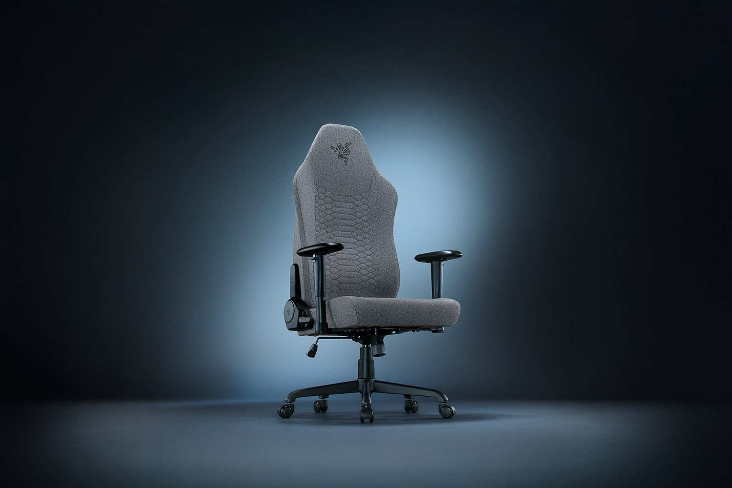 Egy szürke Razer gaming szék kék átmenetes háttéren, karfákkal és a Razer logóval a fejtámlán.