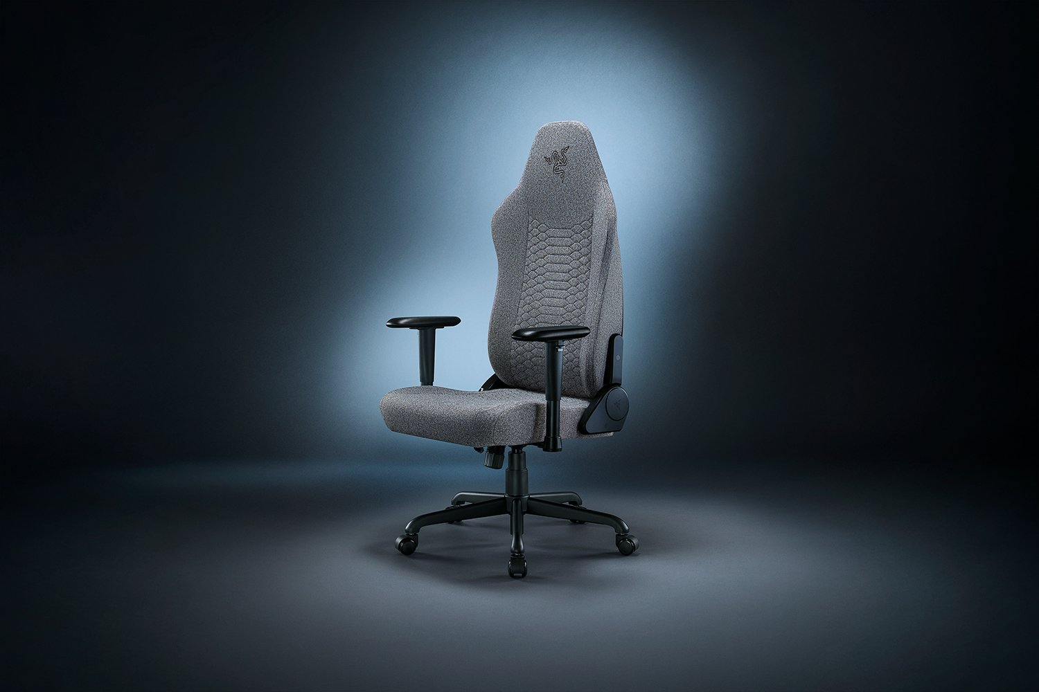 Egy szürke Razer gamer szék fekete karfákkal és alappal, kék-fekete átmenetes háttér előtt.