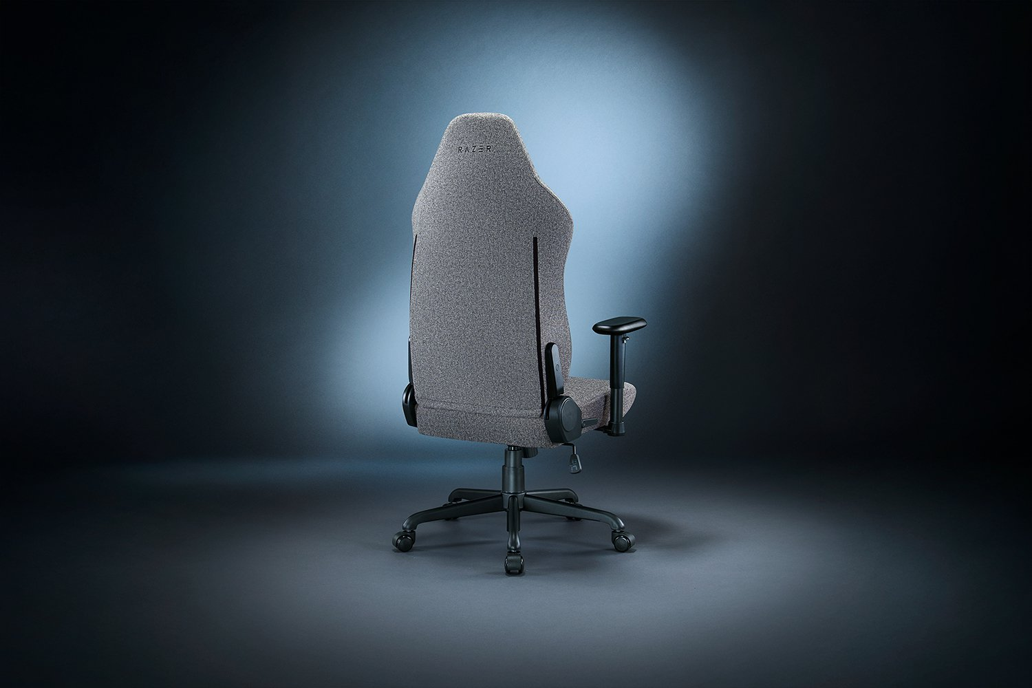 Egy szürke Razer gaming szék hátulról. Fekete kartámaszai és fekete kerekes talpa van. A Razer logó látható.