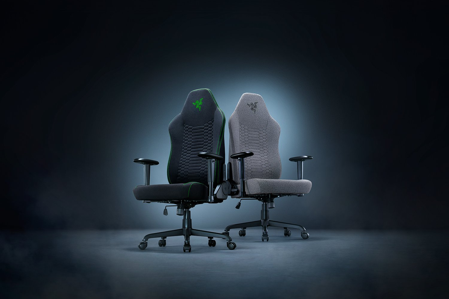 Két gamer szék egymás mellett. Egy fekete zöld díszítéssel, egy szürke. Razer logó látható mindkettőn.