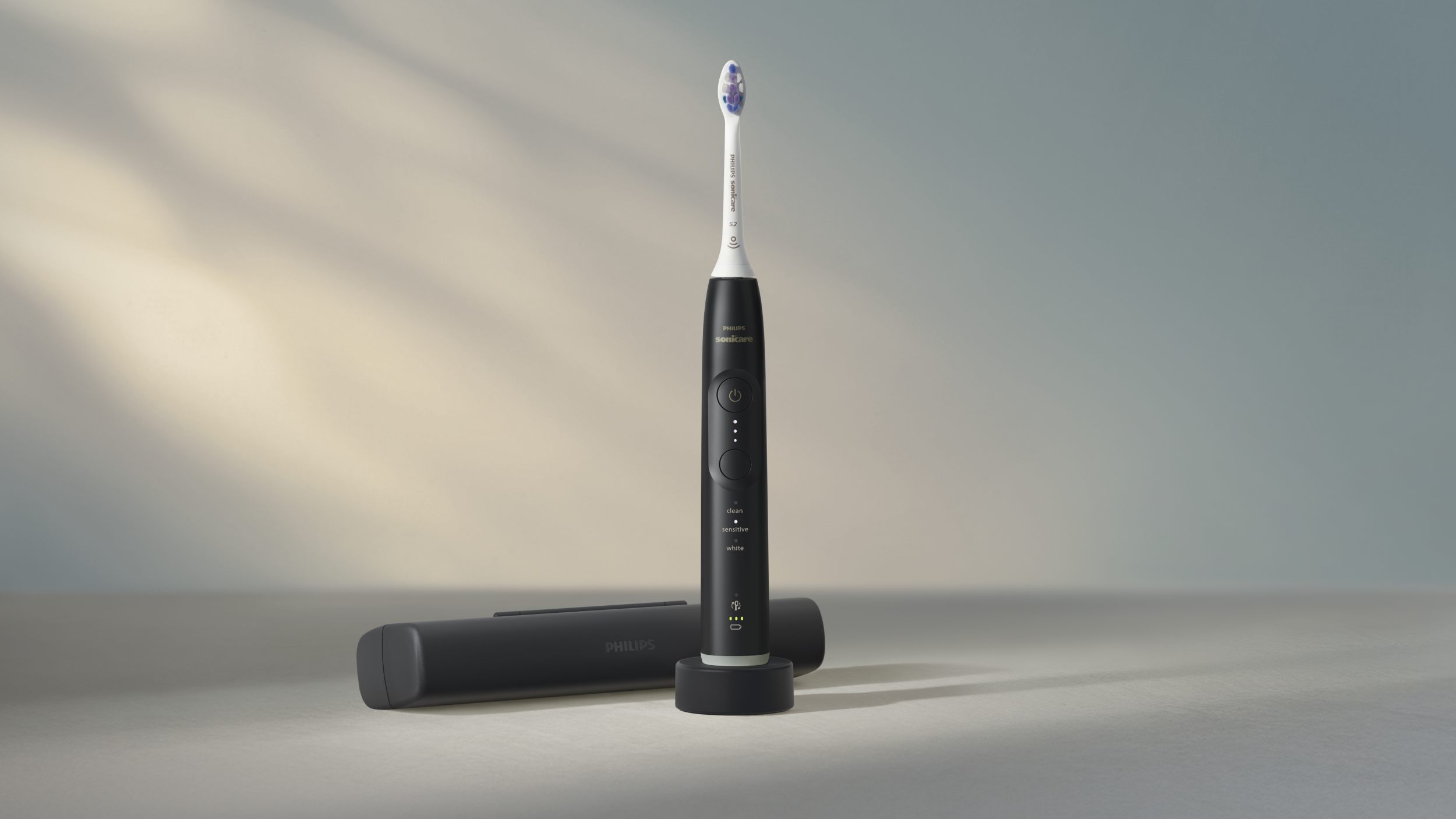 Une brosse à dents Philips Sonicare noire est debout. Un étui et un chargeur sont également présents. Le fond est un dégradé.