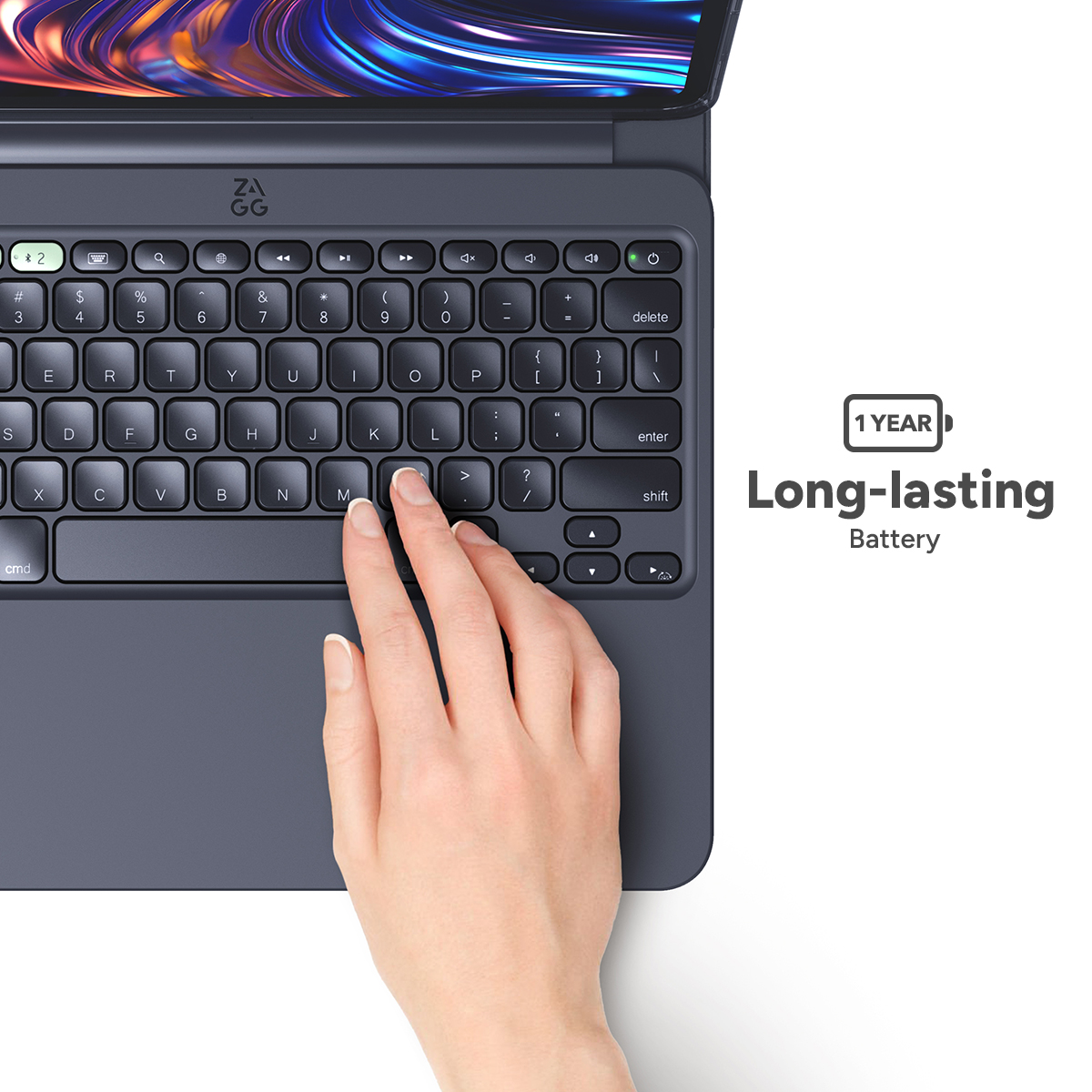Une main appuie sur la touche 'M' d'un clavier bleu foncé. Une tablette est au-dessus du clavier. Le texte dit 'Batterie longue durée'.
