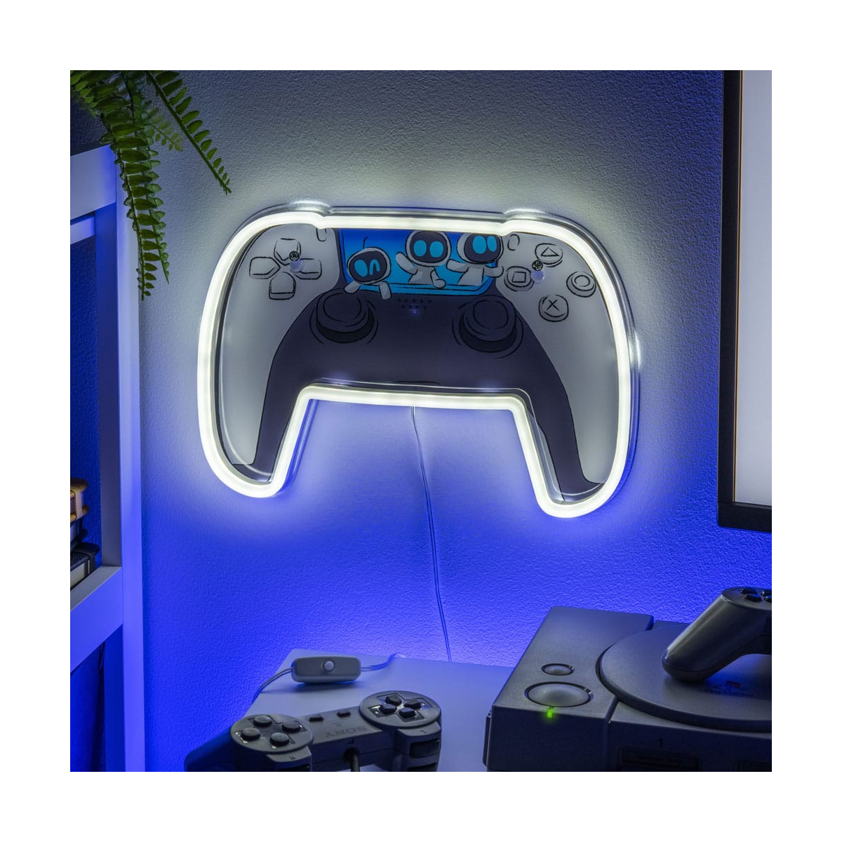 Un mando de juego iluminado con neón decora una pared, la luz azul brilla. Abajo hay mandos y una consola. Un helecho a la izquierda.