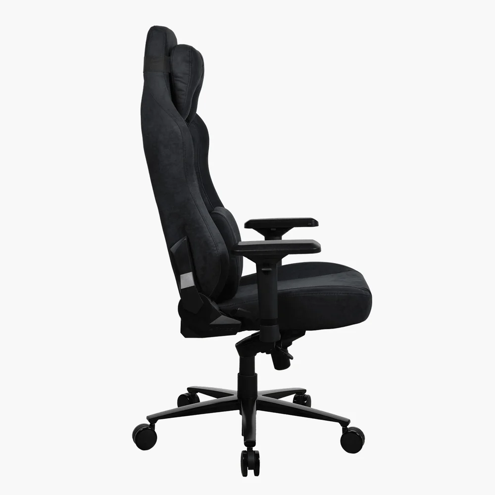 Egy fekete gamer szék profilból. Magas háttámlája, kartámaszai és ötkerekű talpa van, mindez fehér háttér előtt.