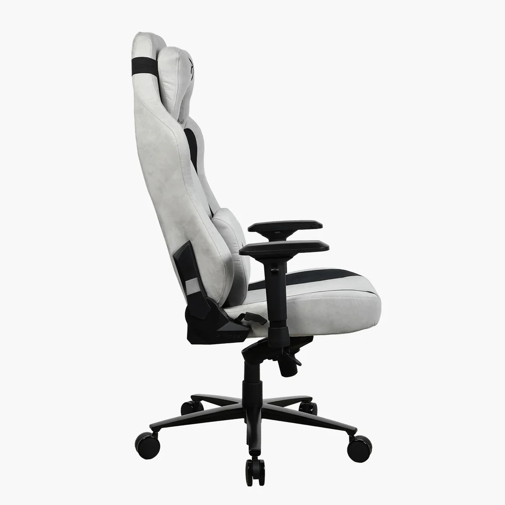 Egy fehér és fekete gamer szék oldalról látható. A szék magas háttámlával és kartámaszokkal rendelkezik, és kerekeken áll.