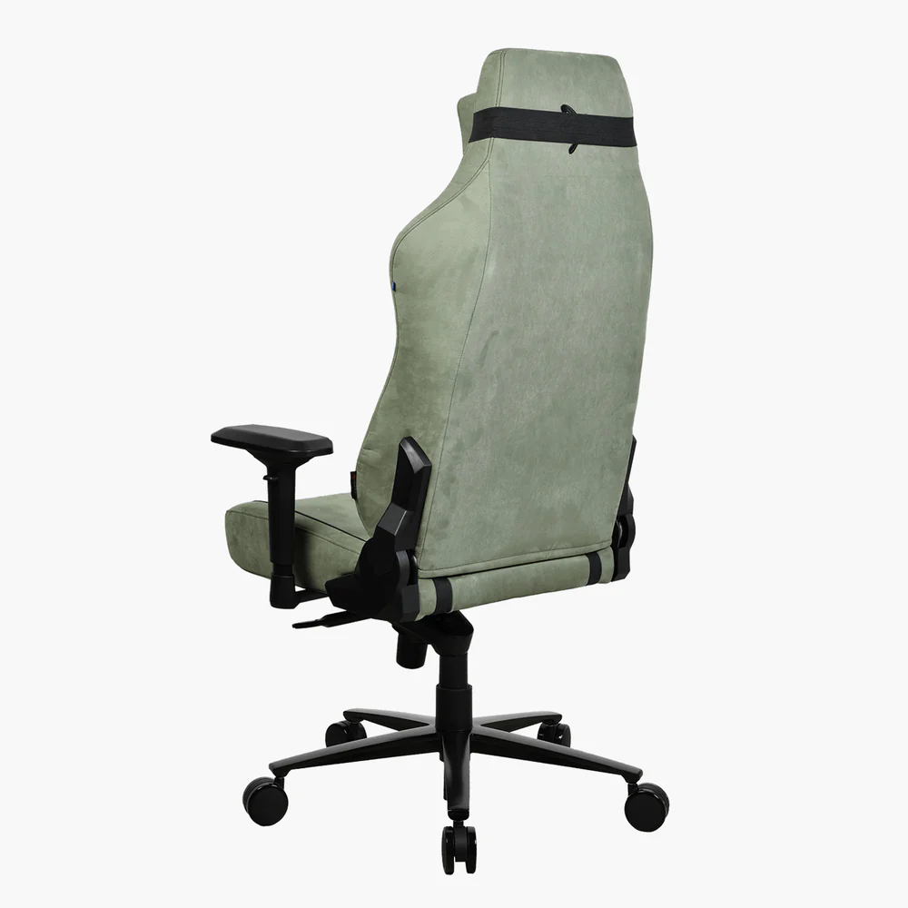 Egy zöld gamer szék. Fekete karfái, fekete kerekes talpa és fekete pántja van a tetején. A háttér fehér.