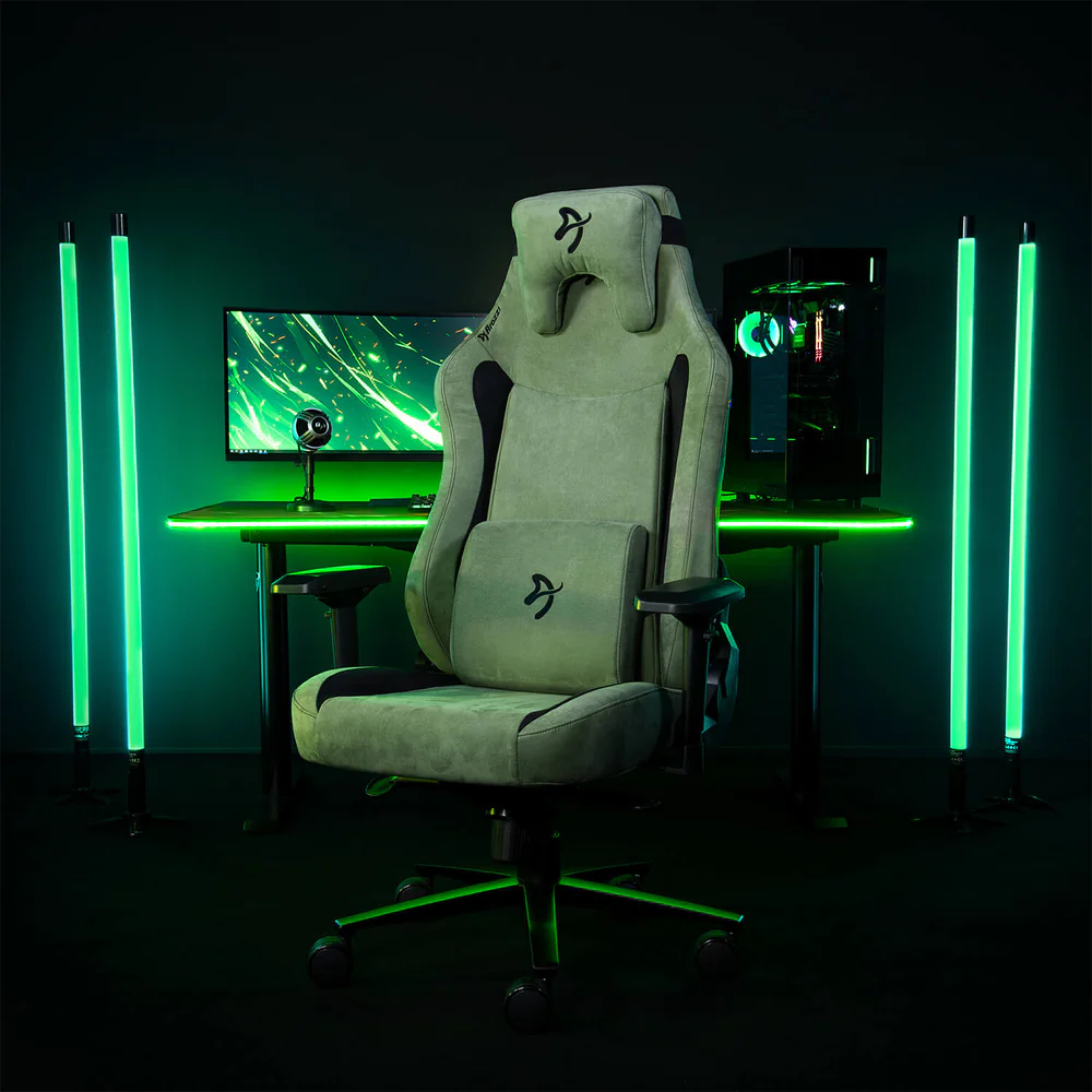 Játék beállítás. Egy zöld szék, asztal és PC zöld lámpákkal megvilágítva. Egy monitor és egy webkamera az asztalon.