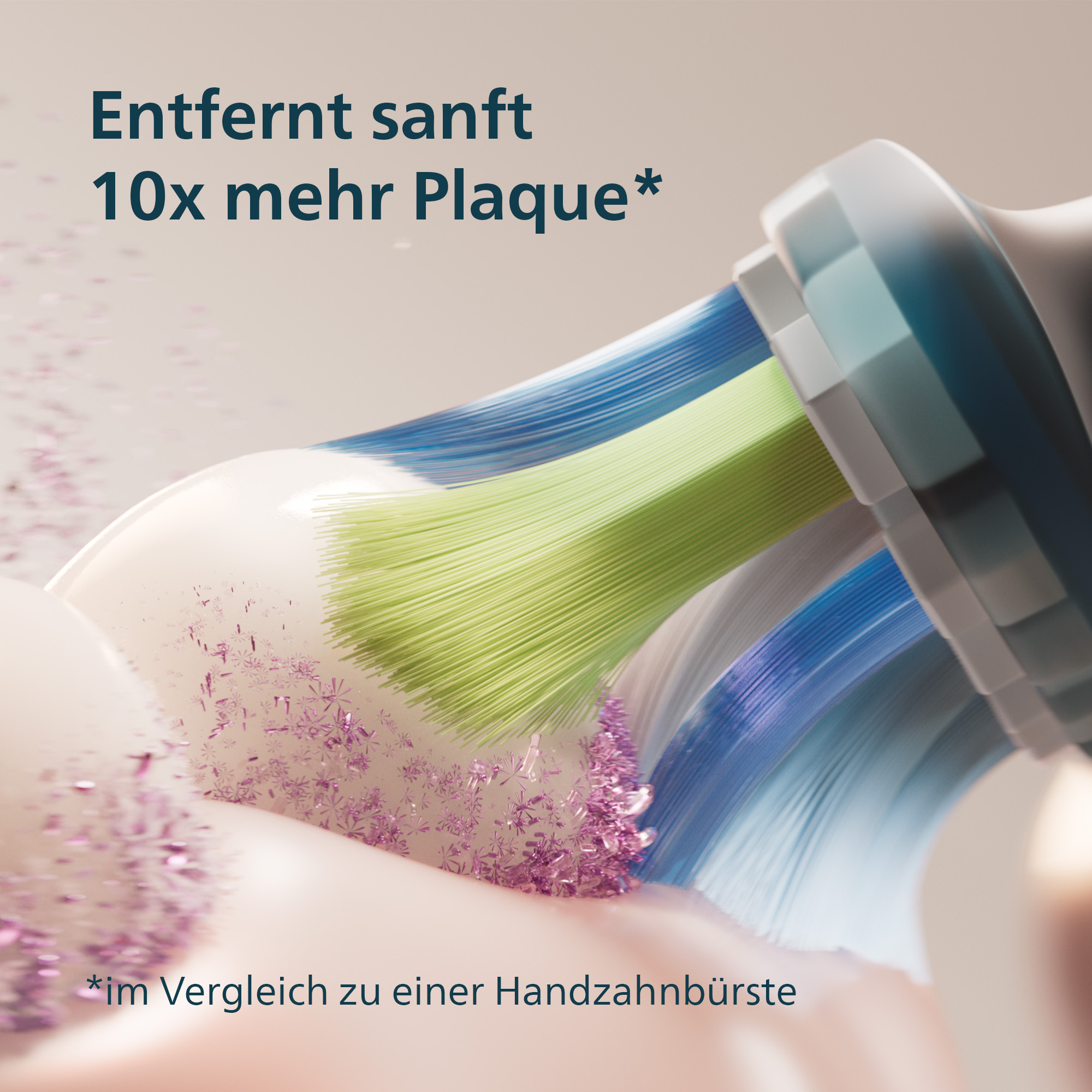 Nahaufnahme einer Zahnbürste mit blauen, grünen und weißen Borsten. Rosa Partikel verstreut, Text: 'entfernt 10x mehr Plaque'.