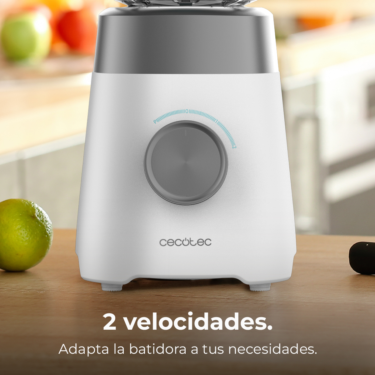 Una batidora blanca y gris con una perilla. Una lima y algunas otras frutas están al lado. El texto dice '2 velocidades. Adapta la batidora a tus necesidades.'