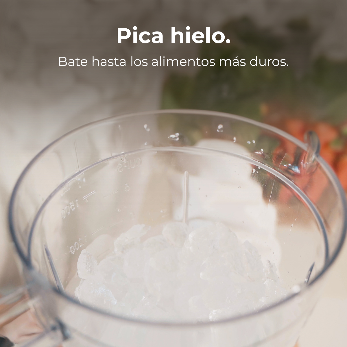 Un recipiente transparente de licuadora lleno de hielo. El texto en la parte superior dice "Pica hielo" y debajo "Bate hasta los alimentos más duros."
