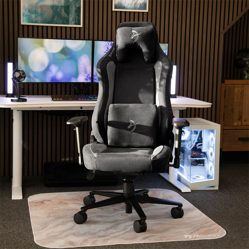 Egy gamer szék márványmintás szőnyegen. Mögötte egy asztal két monitorral és egy számítógép toronnyal.