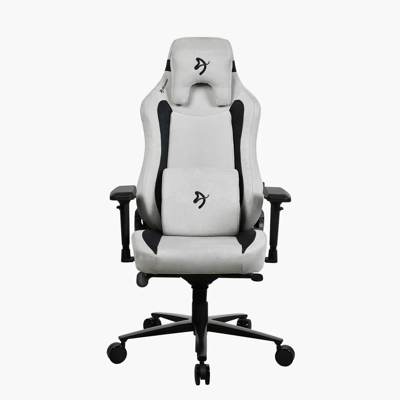 Egy fehér és fekete gamer szék középen. Fejtámlája és derékpárnája van. A szék fekete talpon van kerekekkel.