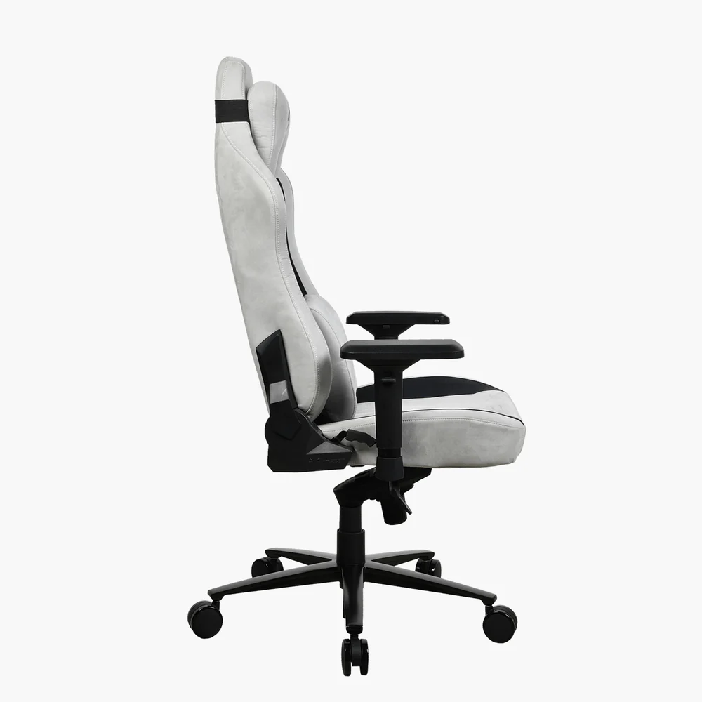 Egy fehér-fekete gamer szék oldalsó nézete fehér háttérrel. Magas háttámla, kartámaszok és ötkerekű talp jellemzi.