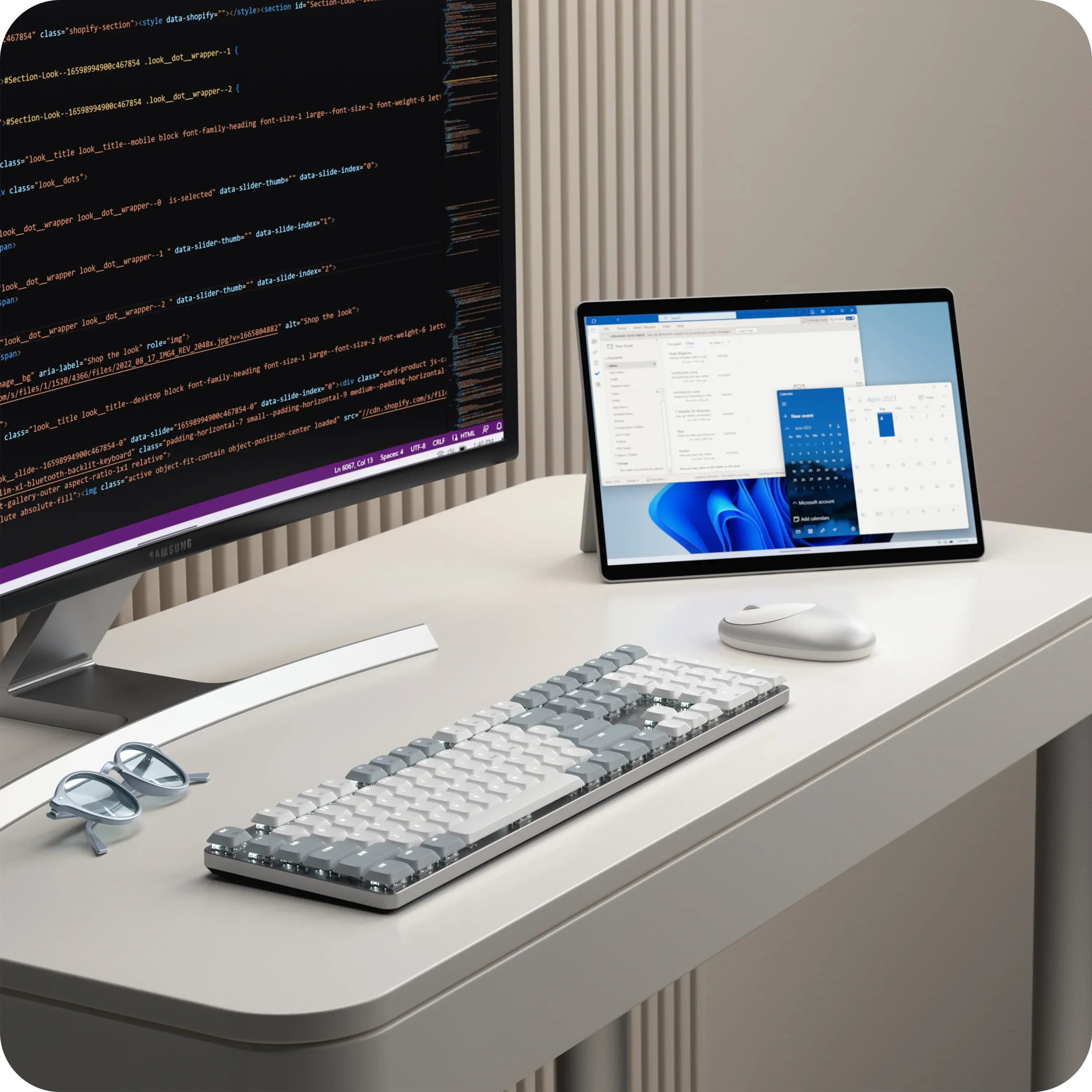 Schreibtisch mit Monitor, der Code zeigt, Tablet mit Kalender, Tastatur, Maus und Brille.