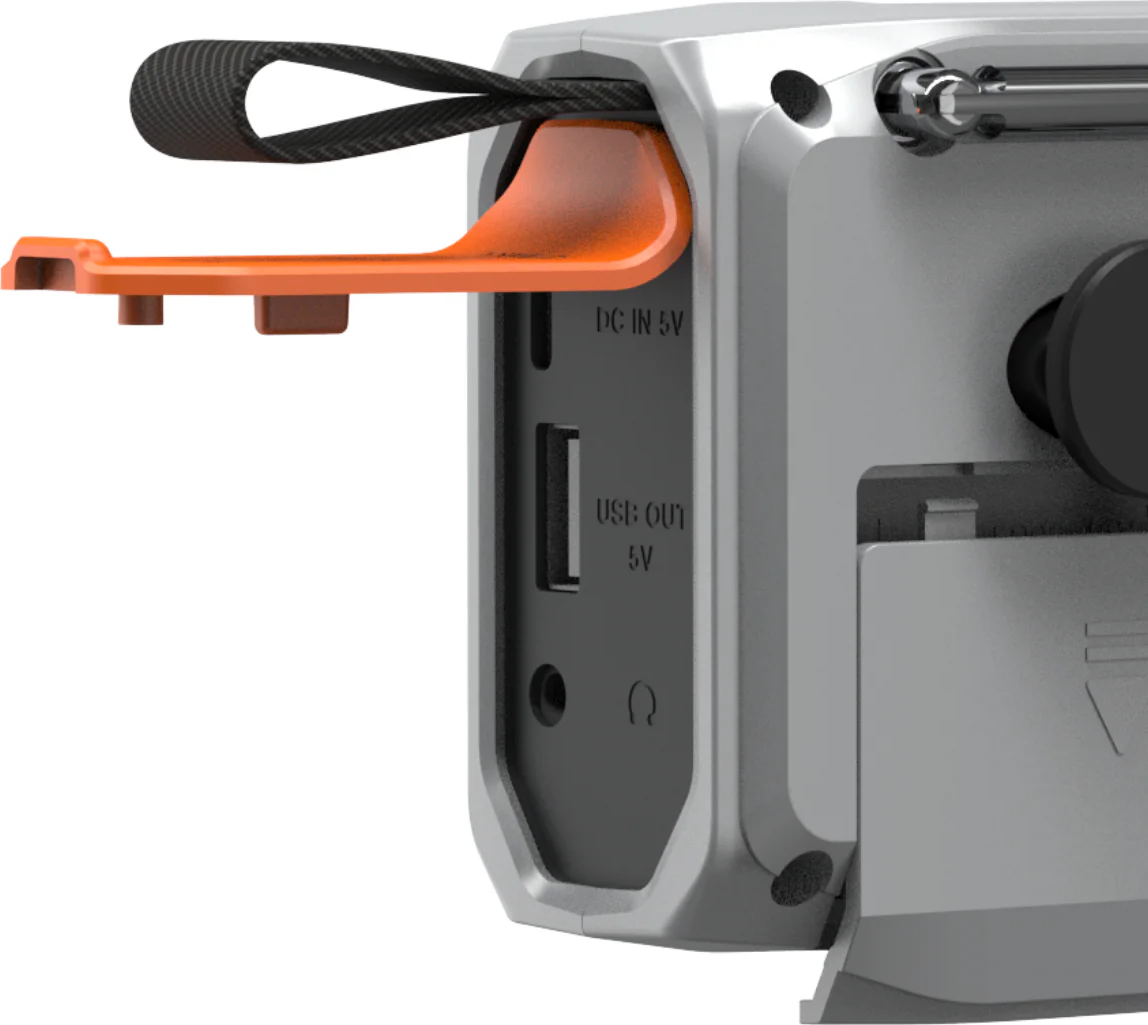 Gros plan d'une radio portable argentée. Comprend une poignée orange, une sangle noire, un port USB et une prise casque. Radio partiellement visible.