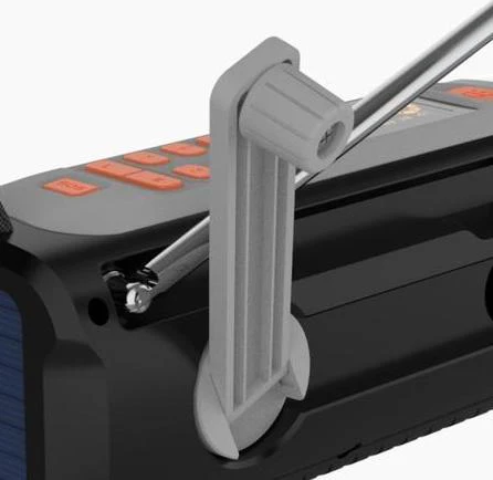 Gros plan d'une radio noire et grise avec des boutons orange et une manivelle grise. La manivelle est au premier plan, la radio en arrière-plan.