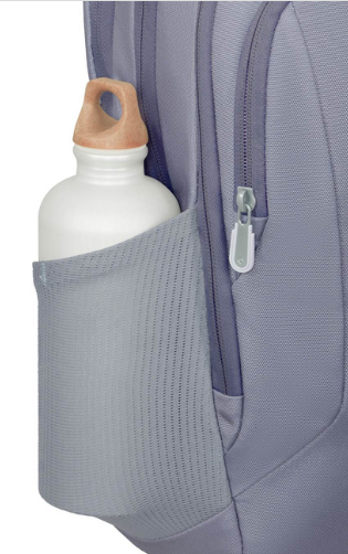 Biała butelka na wodę z drewnianą zakrętką znajduje się w siateczkowej bocznej kieszeni fioletowego plecaka. Widoczny jest również zamek błyskawiczny.