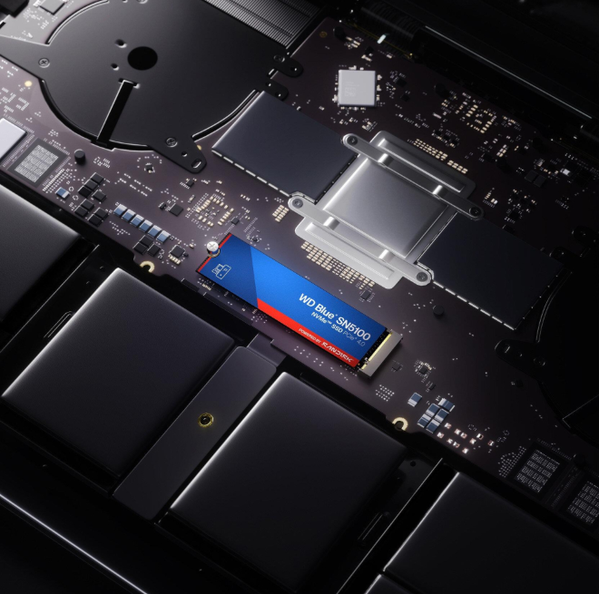 Dysk SSD NVMe WD Blue SN5100 zainstalowany na płycie głównej laptopa, prezentujący elementy wewnętrzne. Dysk SSD ma niebieskie i czerwone detale.