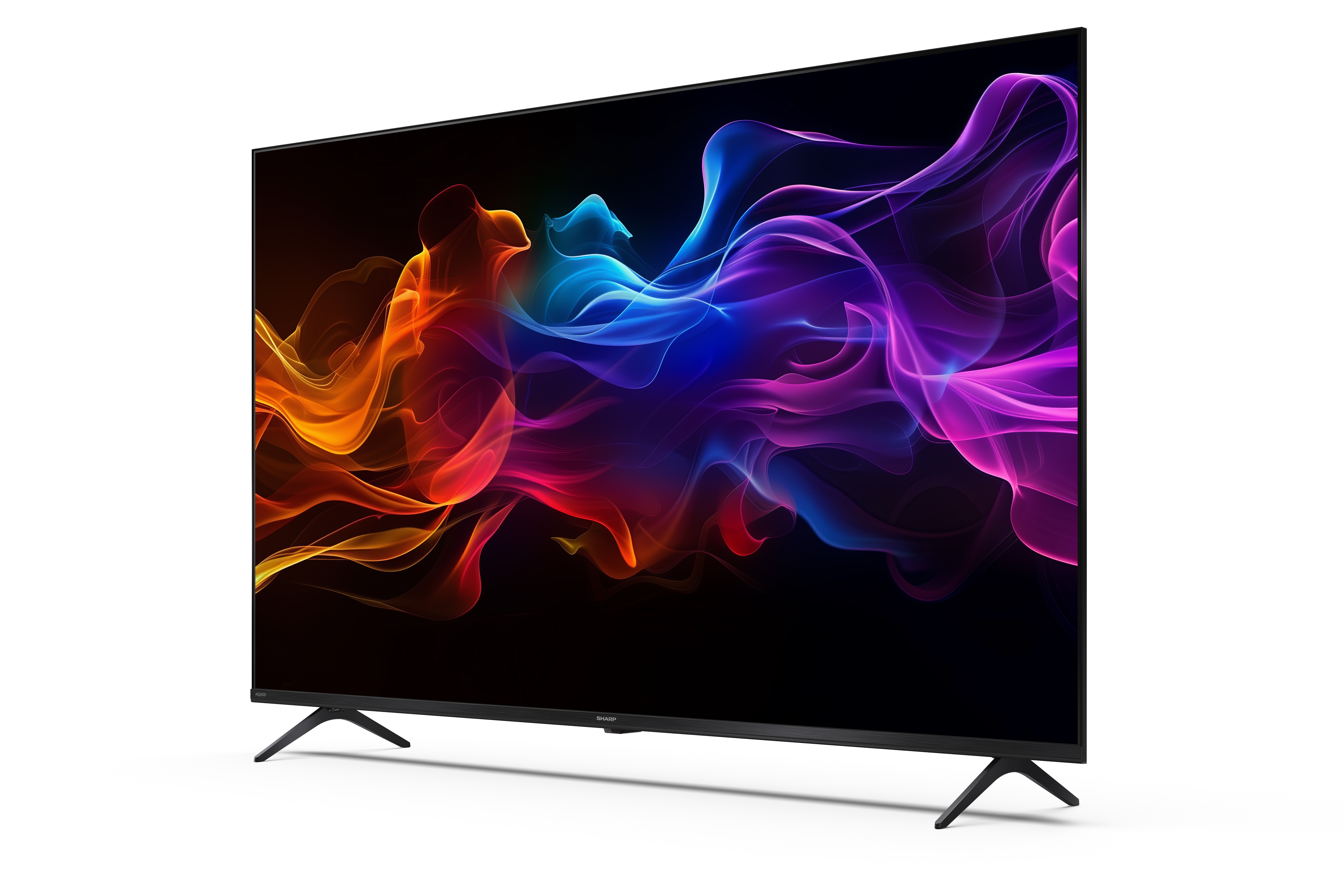 Egy Sharp TV színes, absztrakt hullámokat jelenít meg fekete háttéren. A TV egy fehér felületen van elhelyezve.
