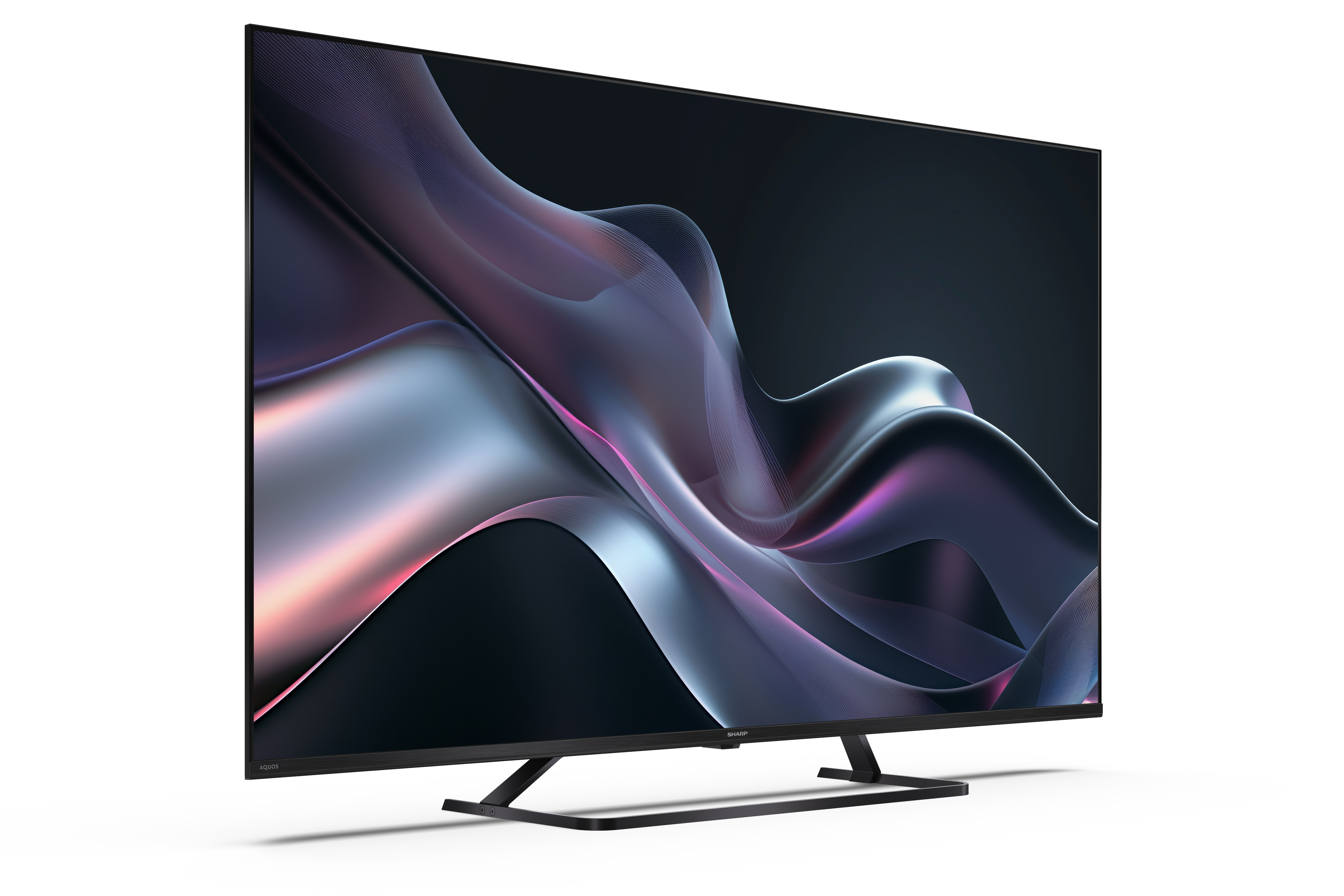Egy Sharp TV sötét absztrakt dizájnnal a képernyőn, fehér felületen állva.