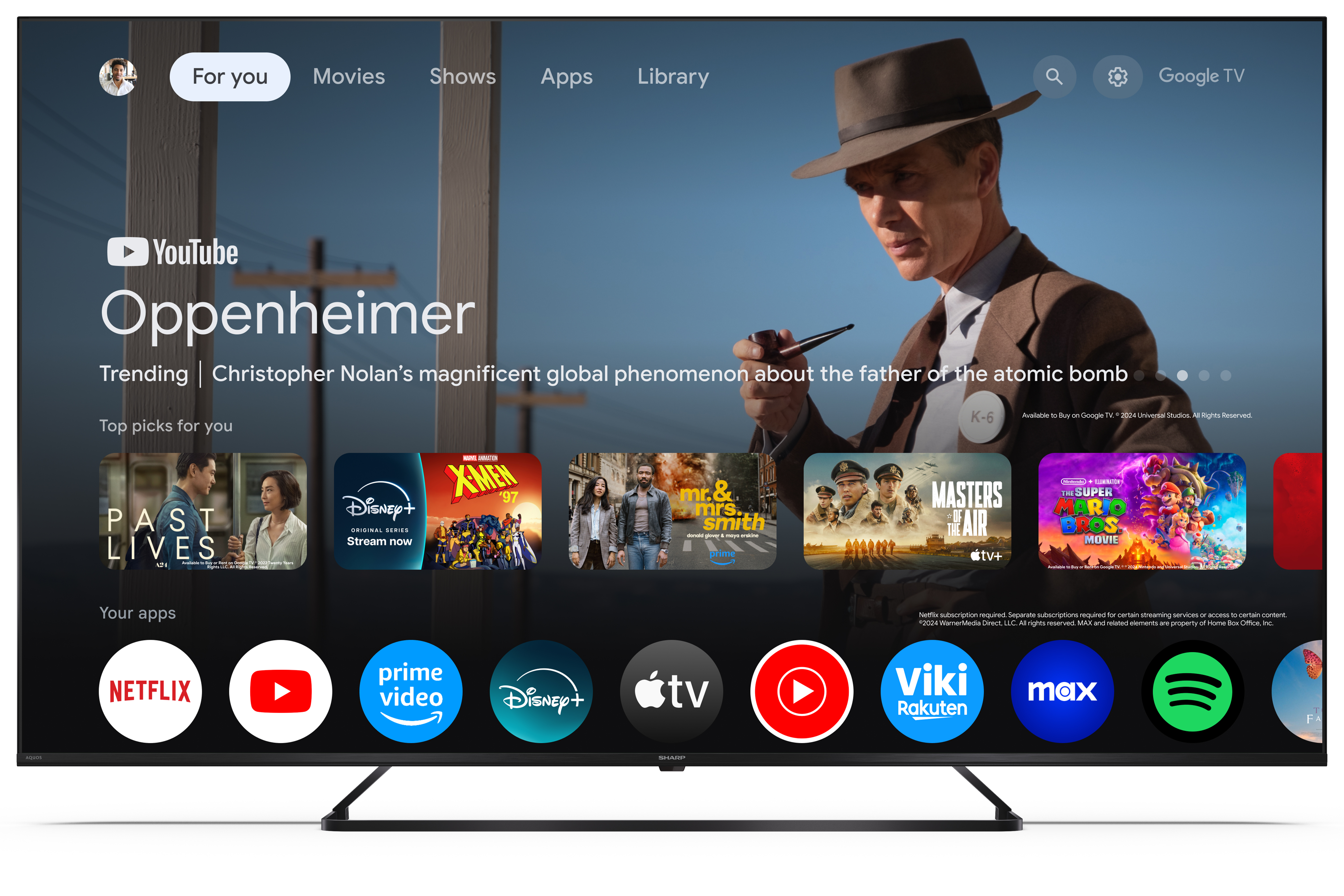 Egy TV-képernyőn az 'Oppenheimer' című film látható, alatta alkalmazásikonokkal. Egy férfi pipát tart.
