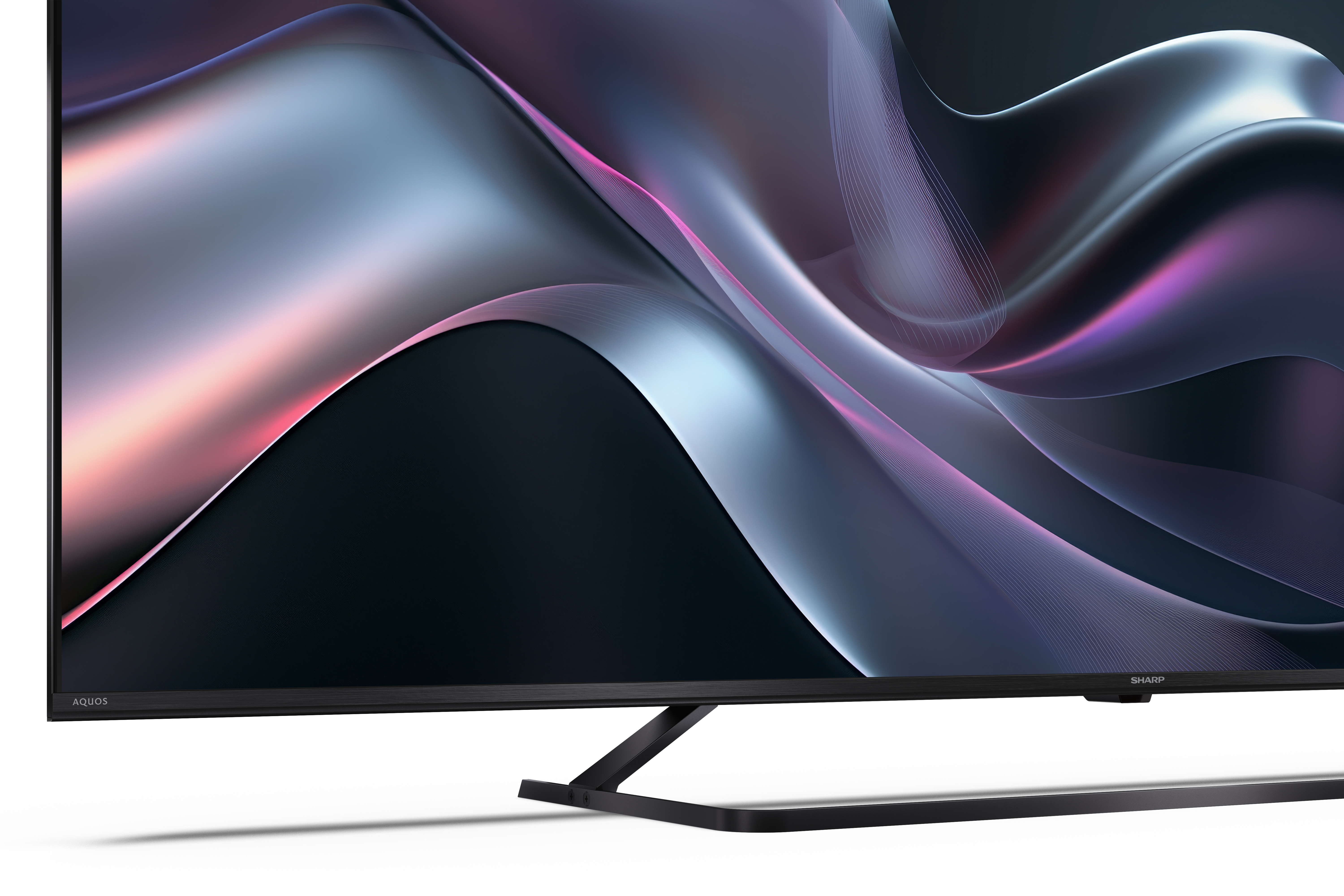 Egy fekete TV-képernyő szürke, lila és rózsaszín árnyalataiban jelenít meg egy folyékony, absztrakt dizájnt. A TV fehér felületen van.