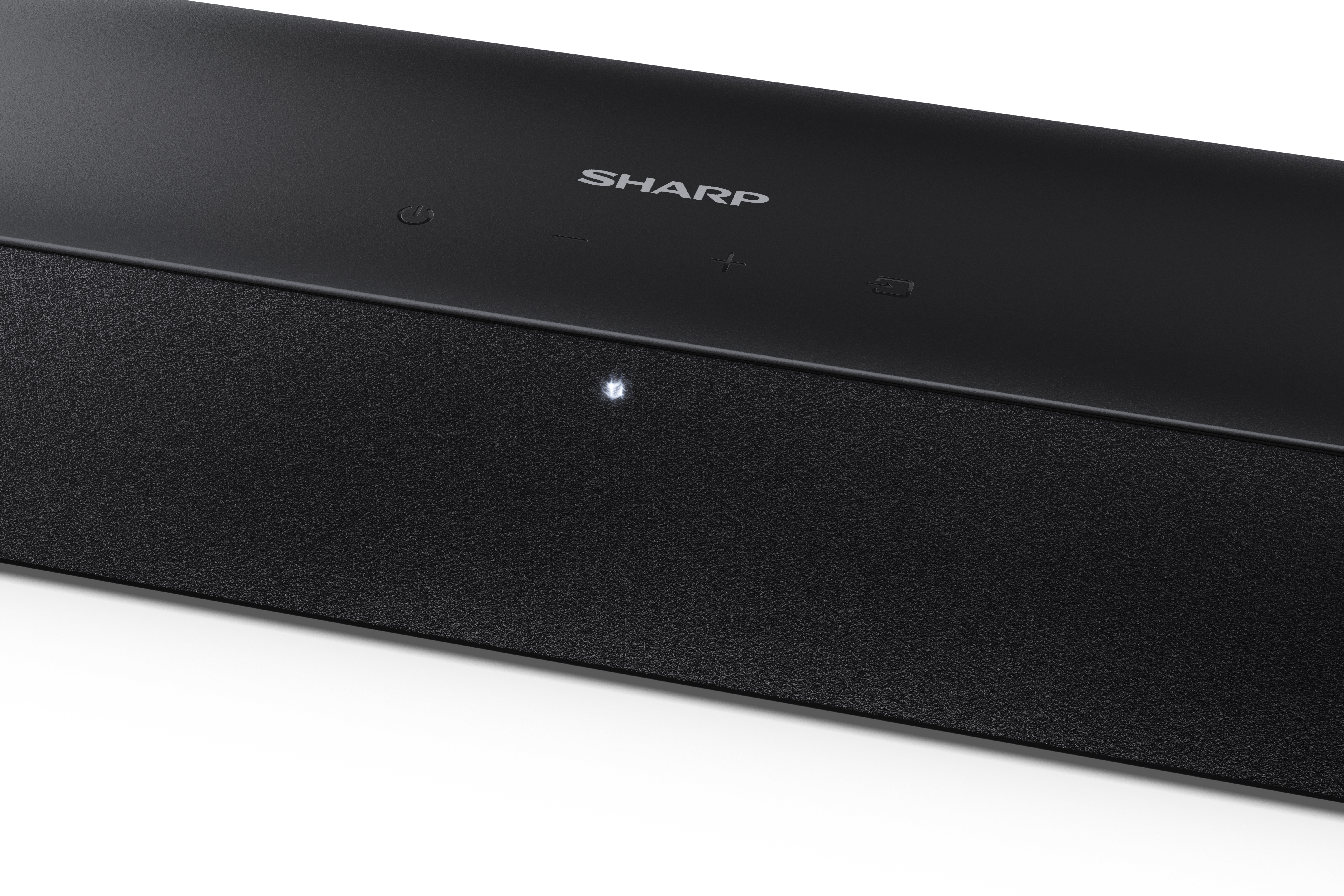 Fekete soundbar, tetején a 'SHARP' márkával. Láthatók a bekapcsoló, hangerő és bemenet gombok. Egy világító fény.